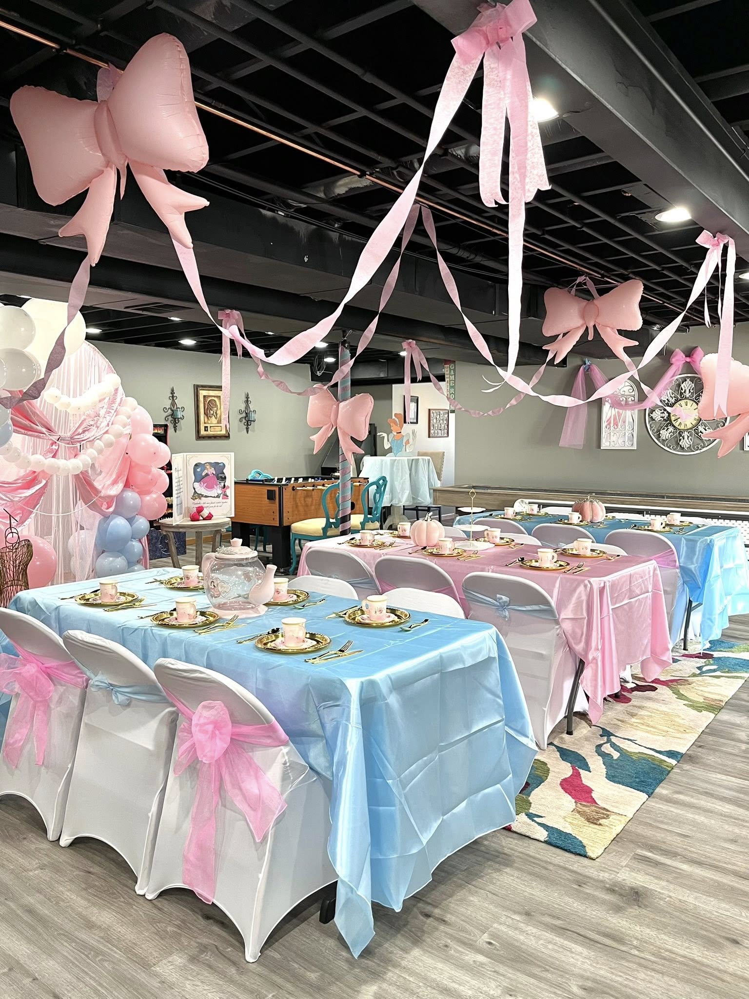 Cinderella themed tea party setup with pink and blue table settings, balloons, and decorative bows.