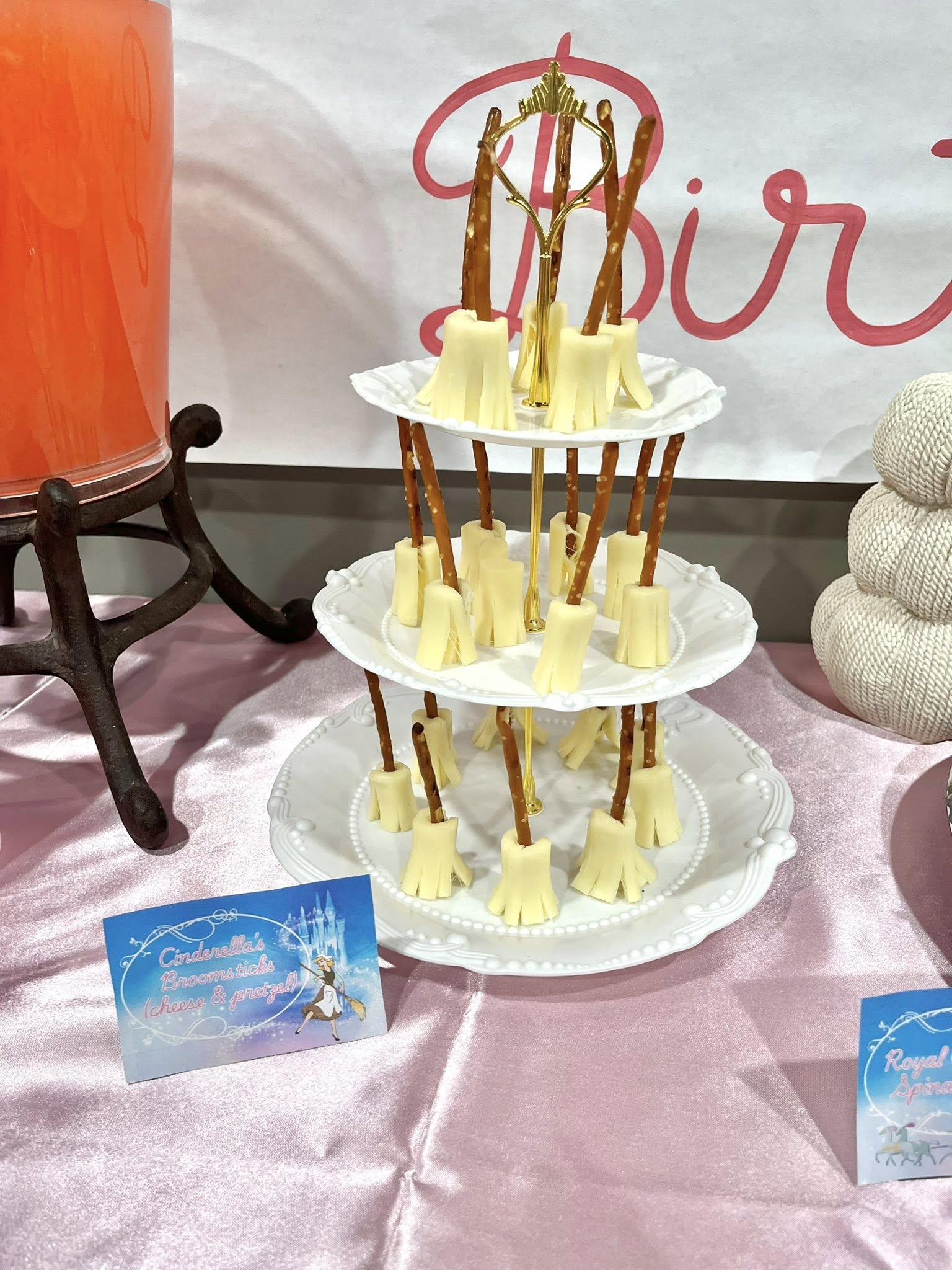Cinderella broomstick snacks made of string cheese and pretzel sticks served on a tiered party tray.