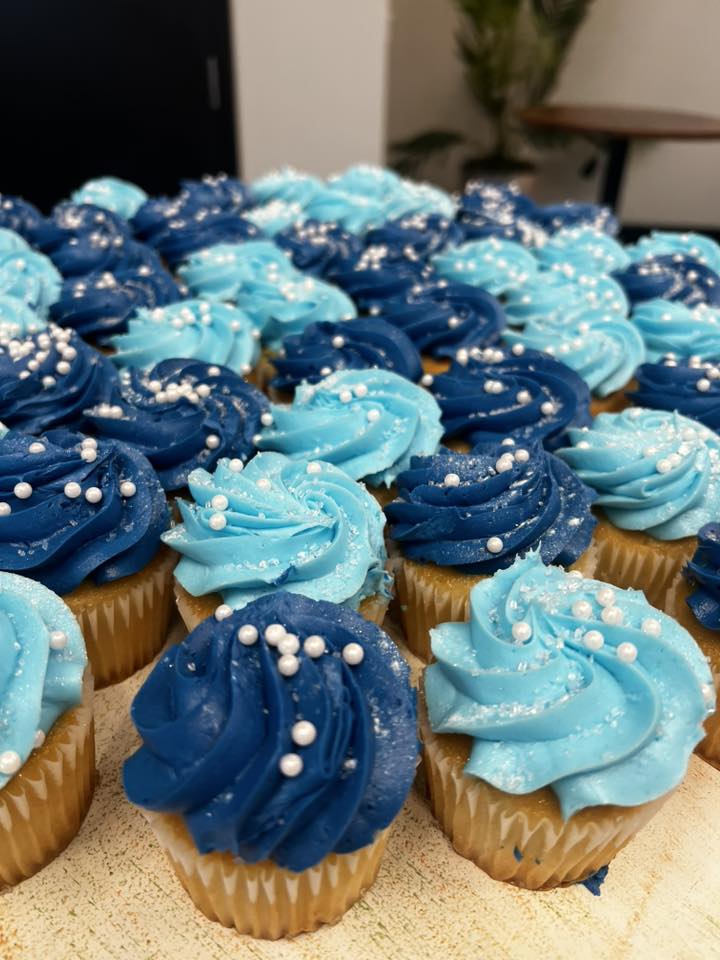 Platter of cupcakes with swirls of navy and light blue frosting topped with white pearl sprinkles