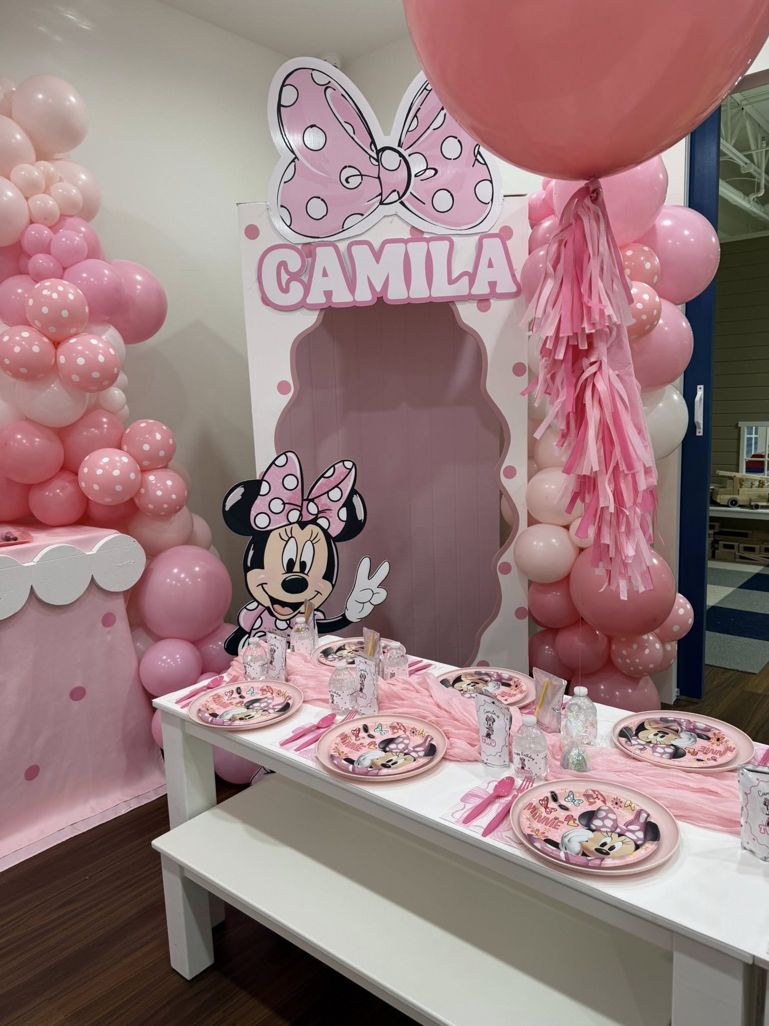 Minnie Mouse themed birthday party setup with pink balloon decorations and personalized table settings for Camila.