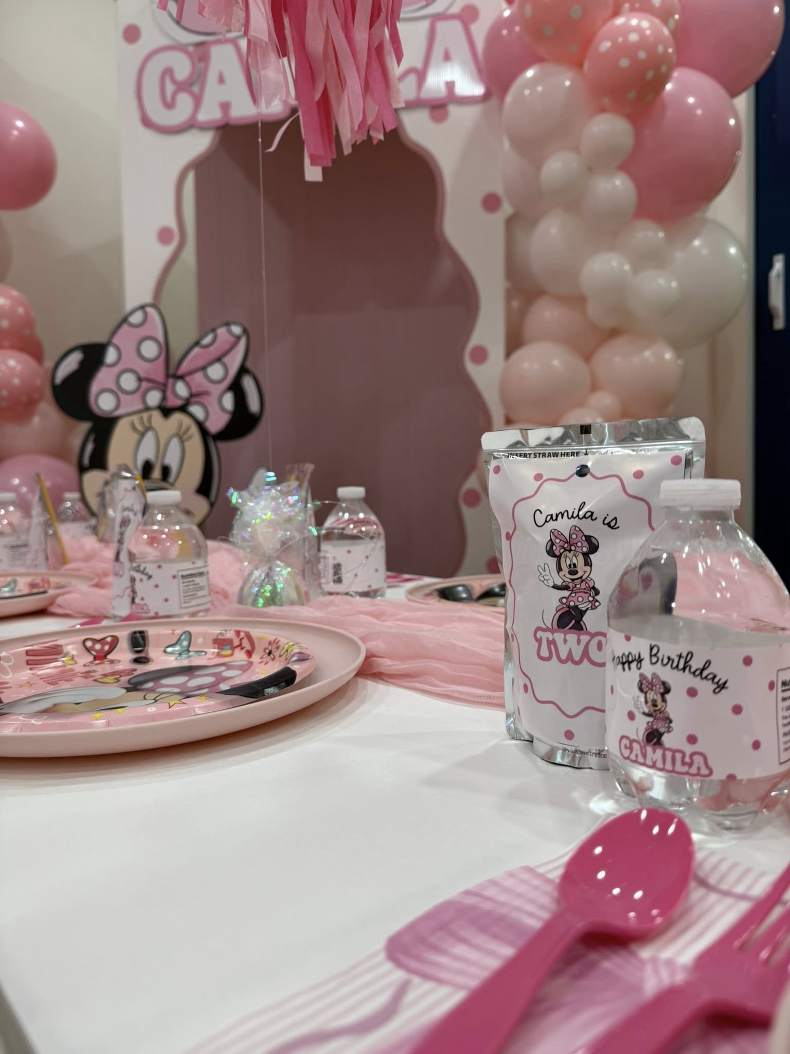 Minnie Mouse themed birthday party table setting with personalized water bottles and plates for Camila's second birthday.
