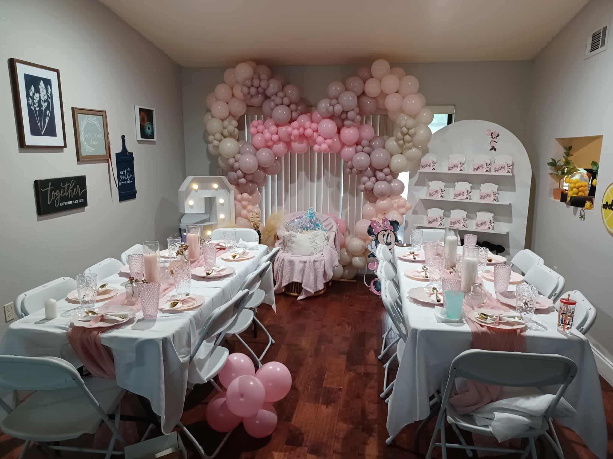 Minnie Mouse themed birthday party setup with balloon arches, table settings, and personalized favor boxes.