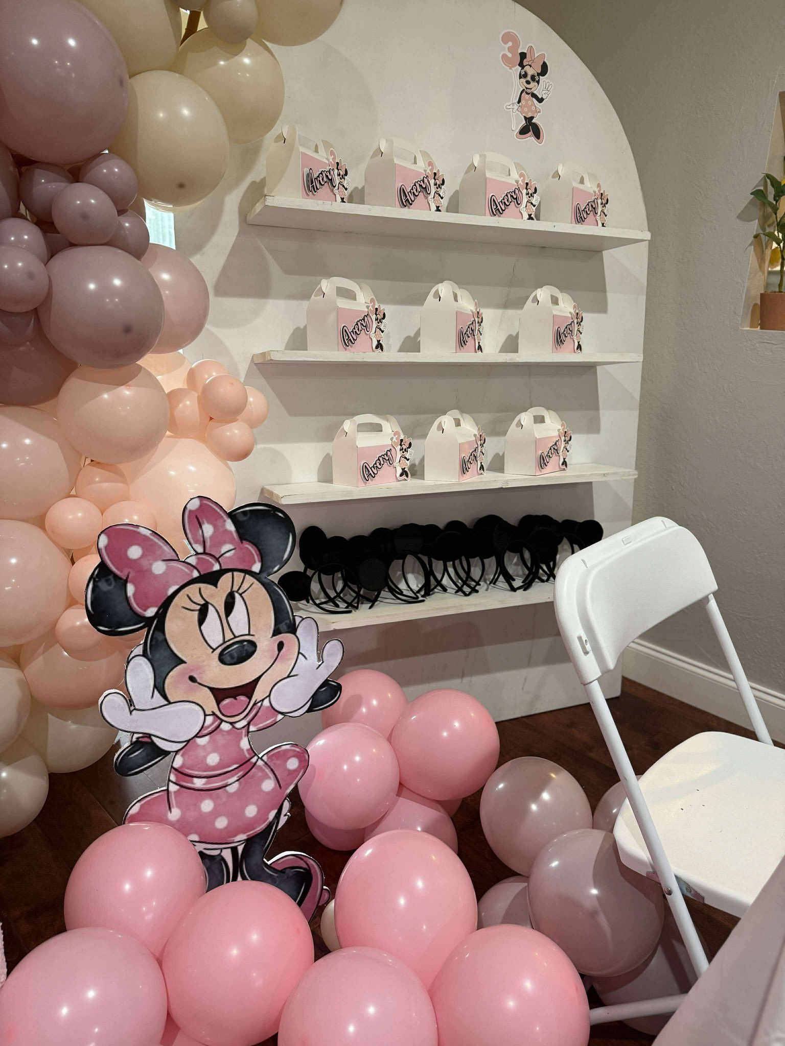 Minnie Mouse themed birthday party decorations with pastel balloons, favor boxes labeled Avery, and mouse ears.
