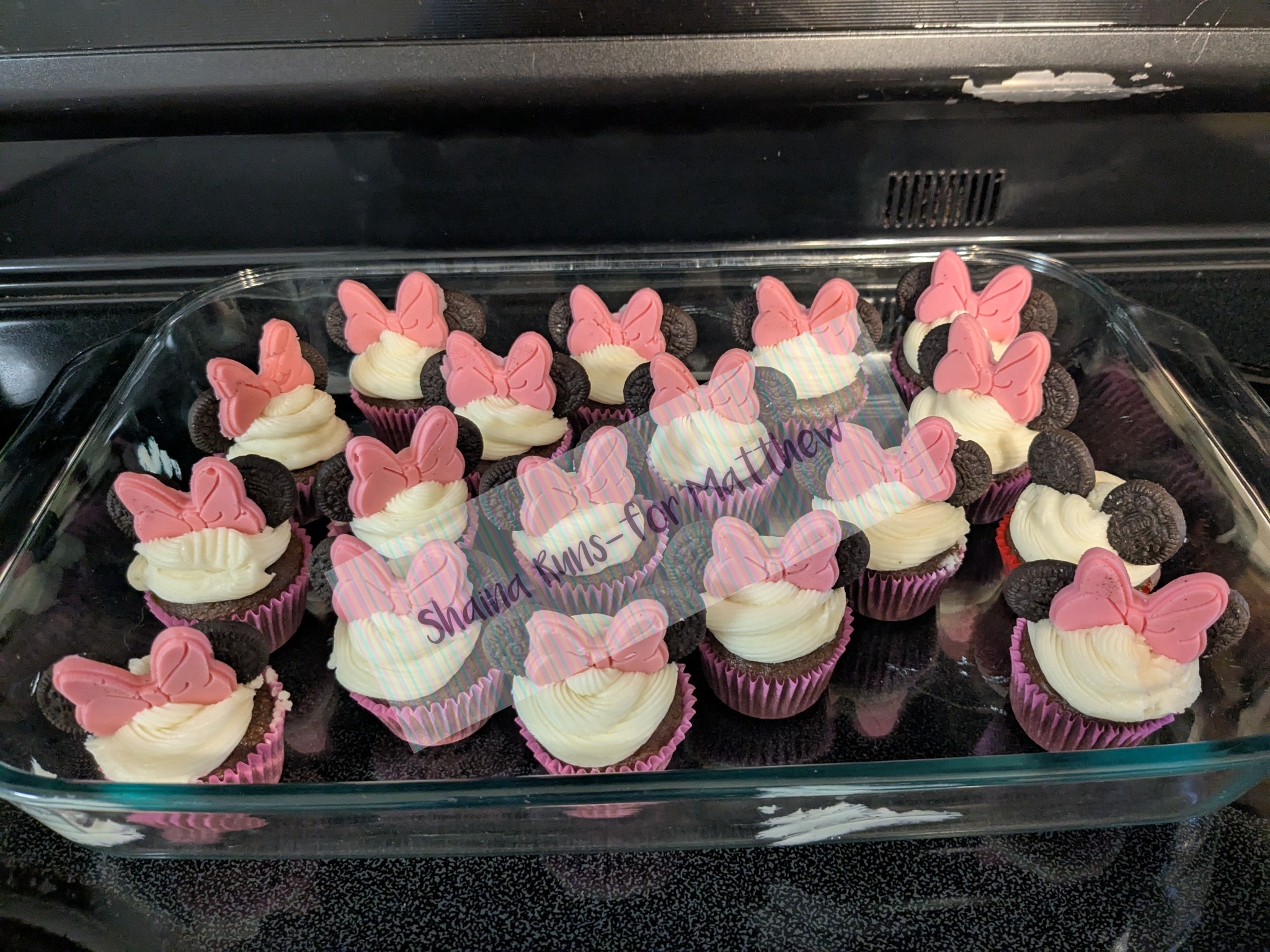 Homemade cupcakes decorated with vanilla frosting, Oreo ears, and pink fondant Minnie Mouse bows