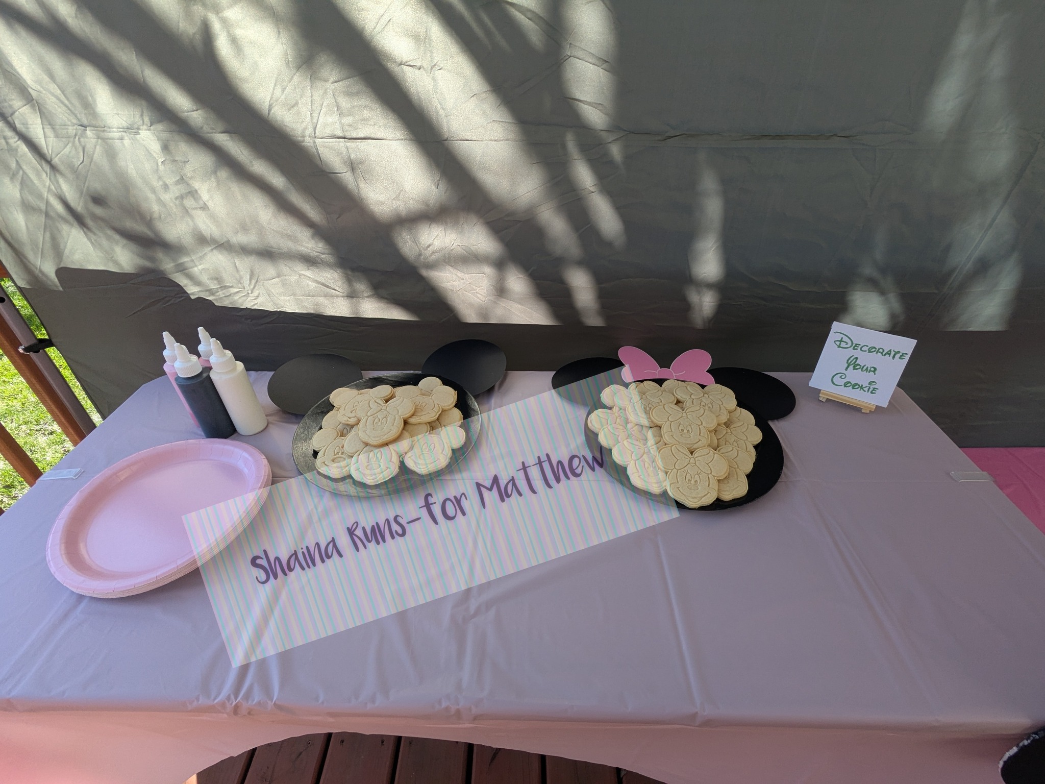 Table set up for a children's party with Minnie Mouse shaped cookies, icing bottles, and a Decorate Your Cookie sign.