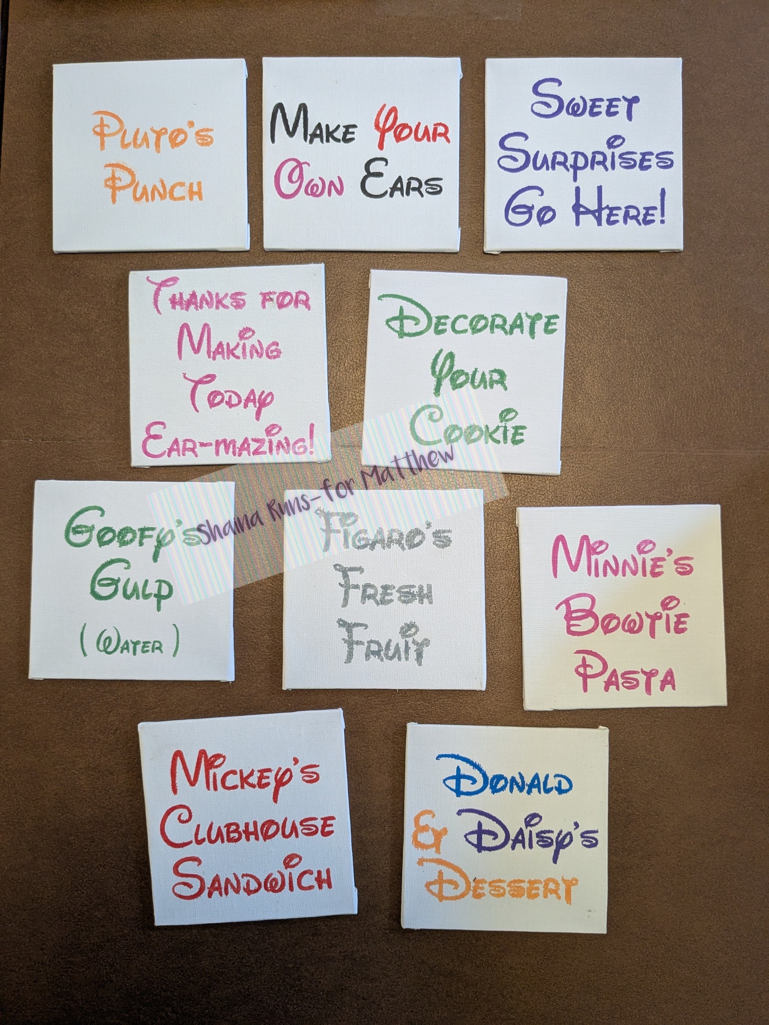 Set of ten small Disney-themed food and activity station signs with colorful text on white backgrounds.
