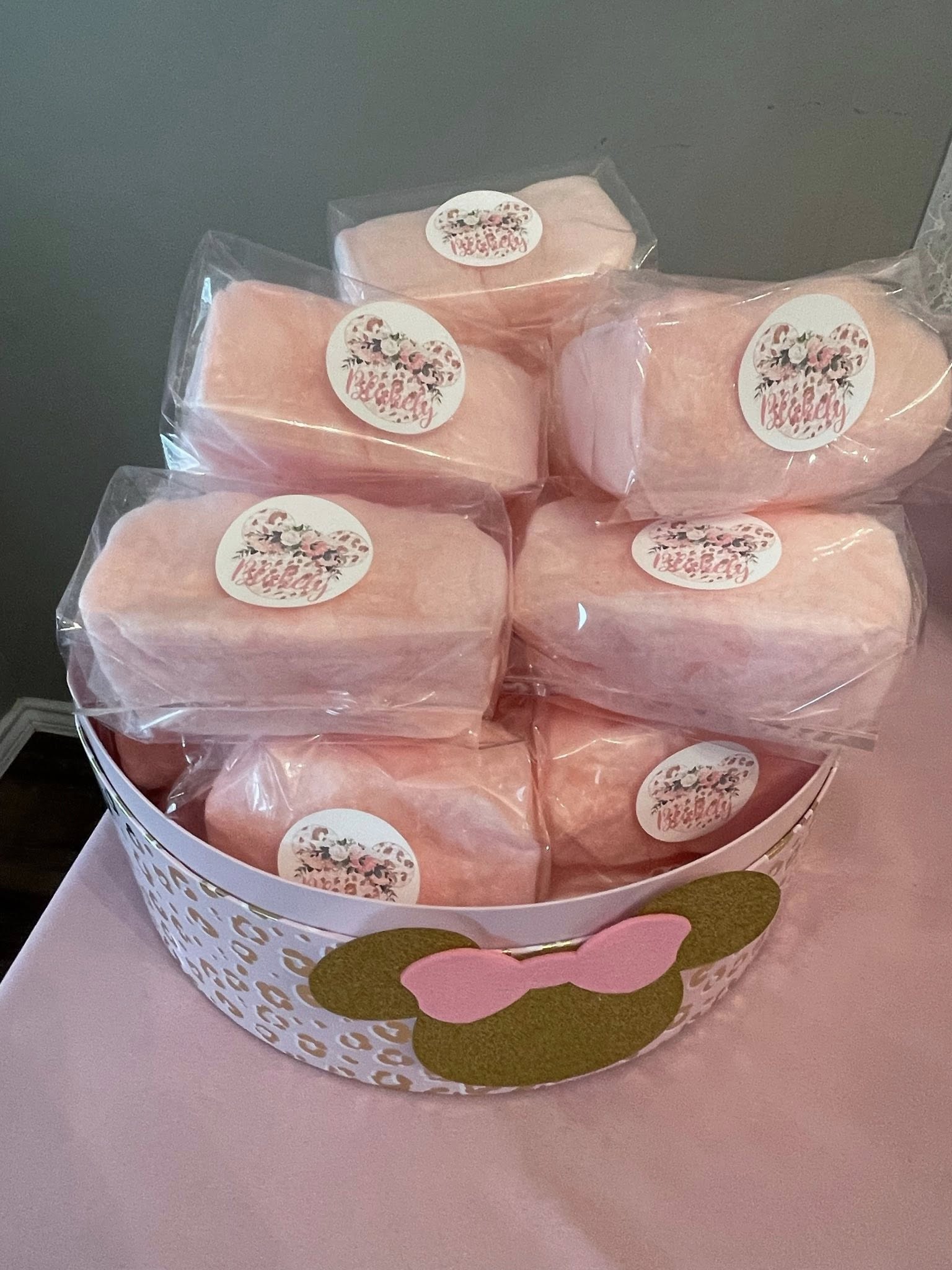 Individually wrapped pink cotton candy bags with custom floral leopard print mouse-ear stickers in a themed basket