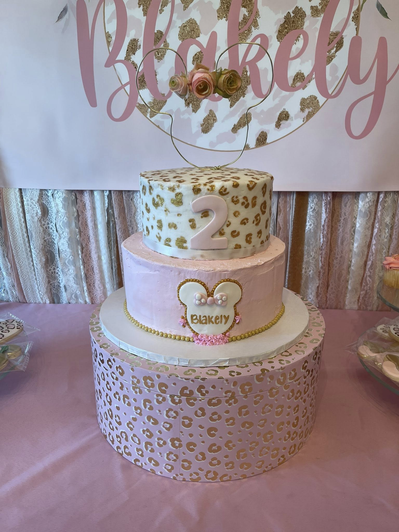Two-tier pink and gold leopard print birthday cake for a 2nd birthday with Minnie Mouse themed name plaque