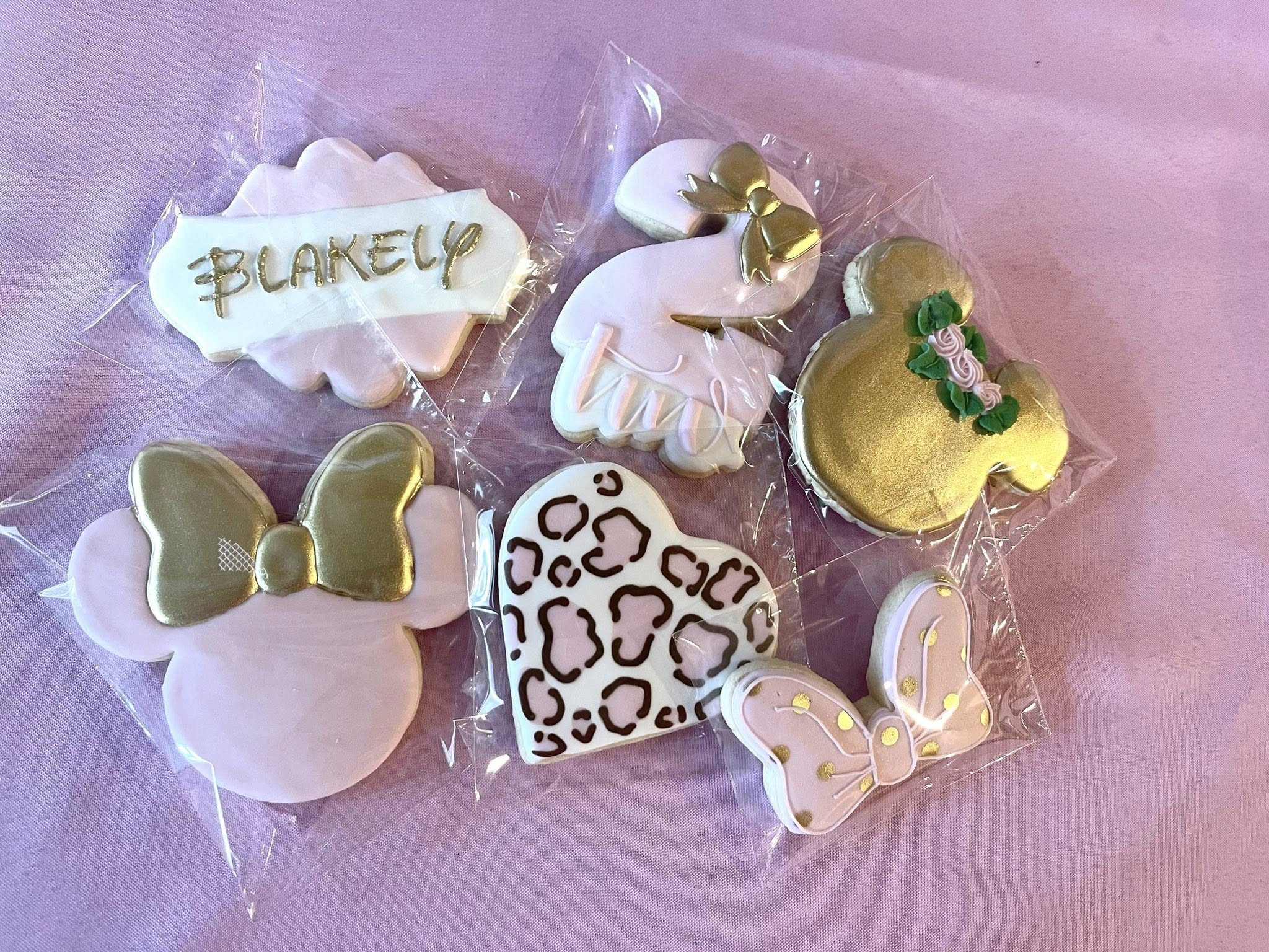 Custom set of pink and gold birthday sugar cookies including a name plaque, number two, and mouse ears.