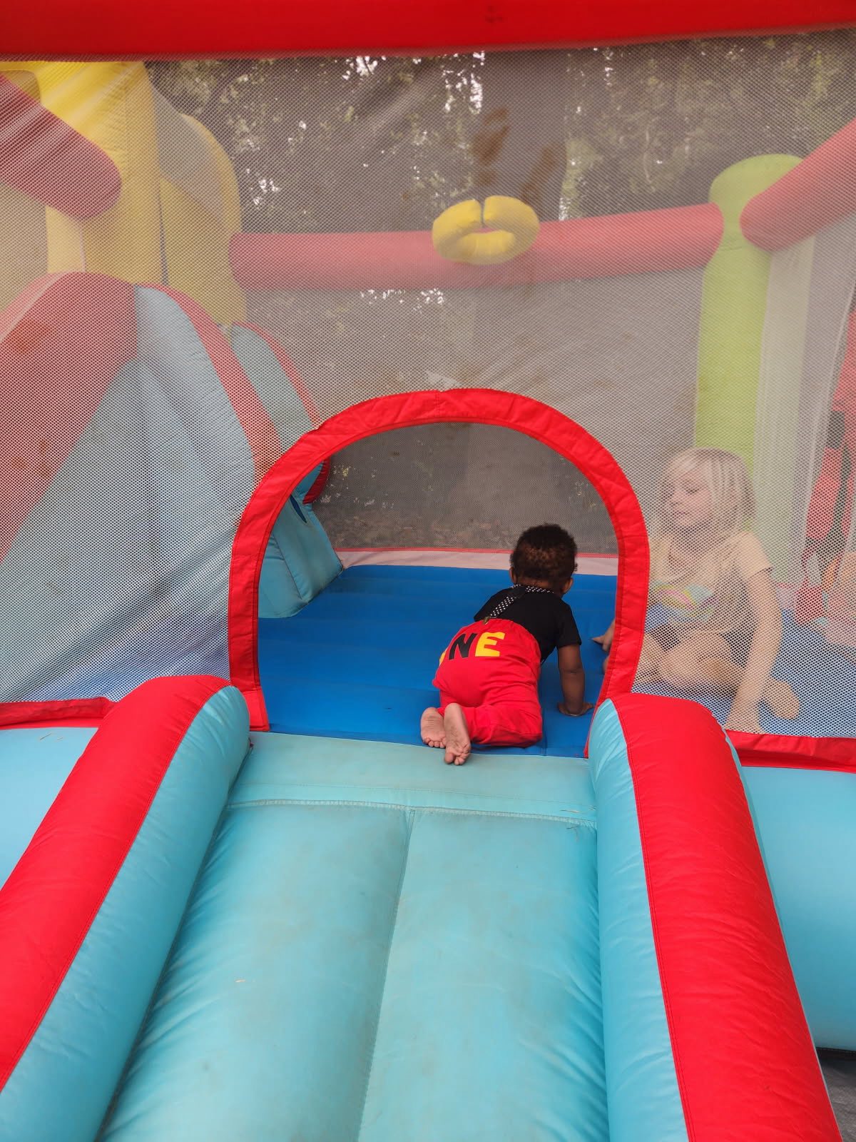 Toddler crawling inside a colorful backyard bounce house