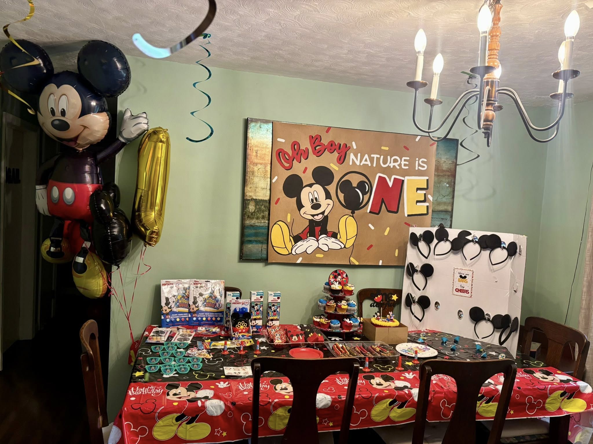 Table set for a Mickey Mouse themed first birthday party with decorations and party favors.