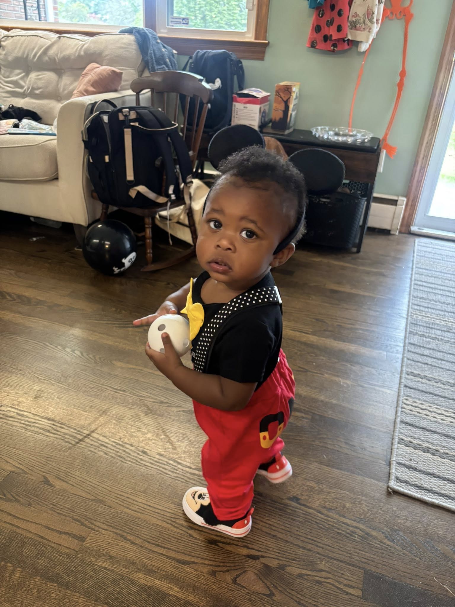 Toddler wearing a Mickey Mouse costume with ears and patterned suspenders