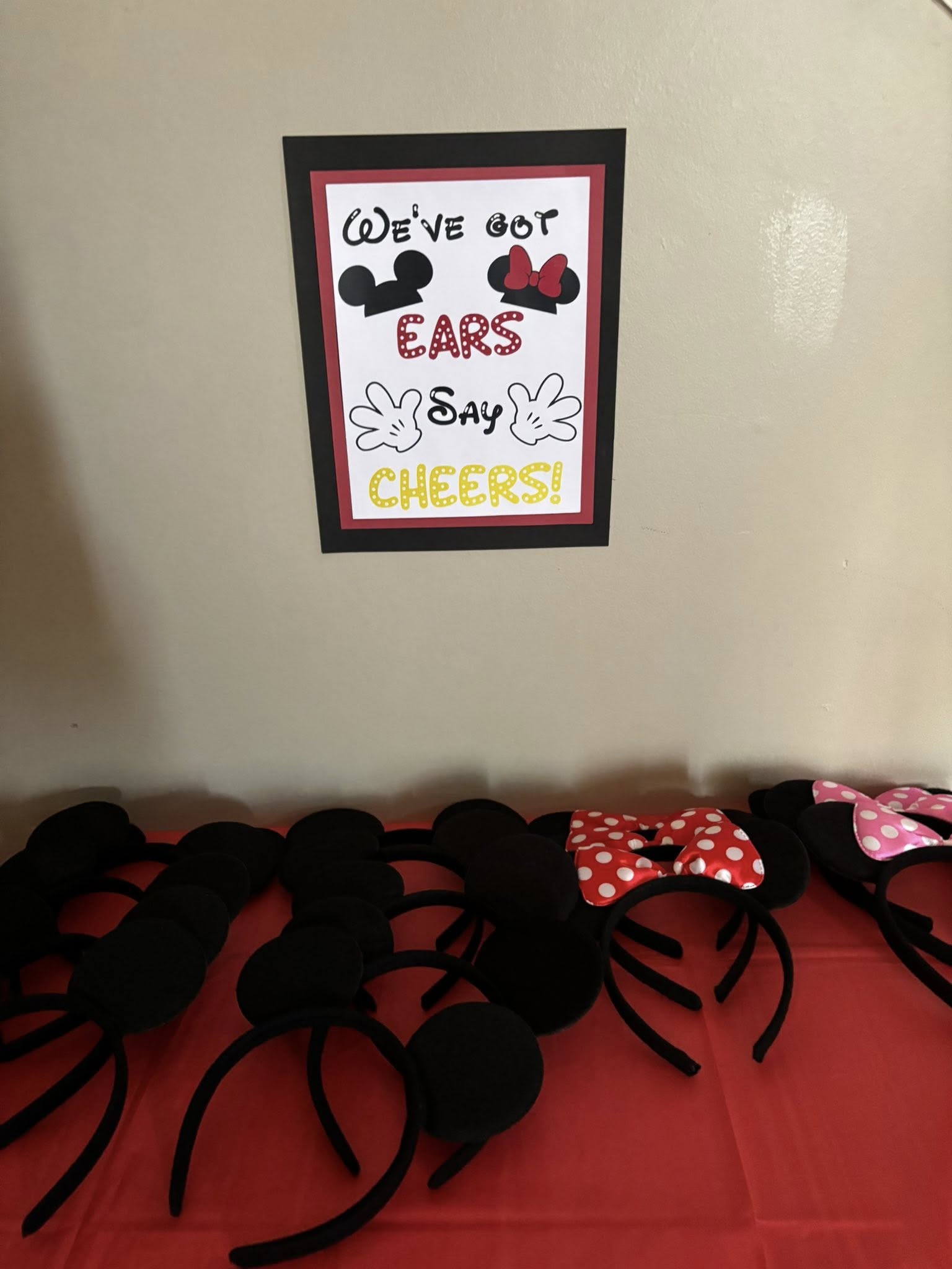 Display of party mouse ear headbands on a table with a sign reading We've Got Ears Say Cheers