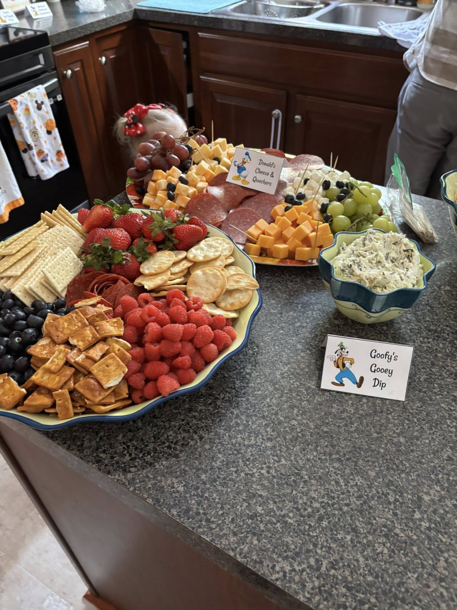 Charcuterie boards and dip displayed with Disney-themed name cards for a party.