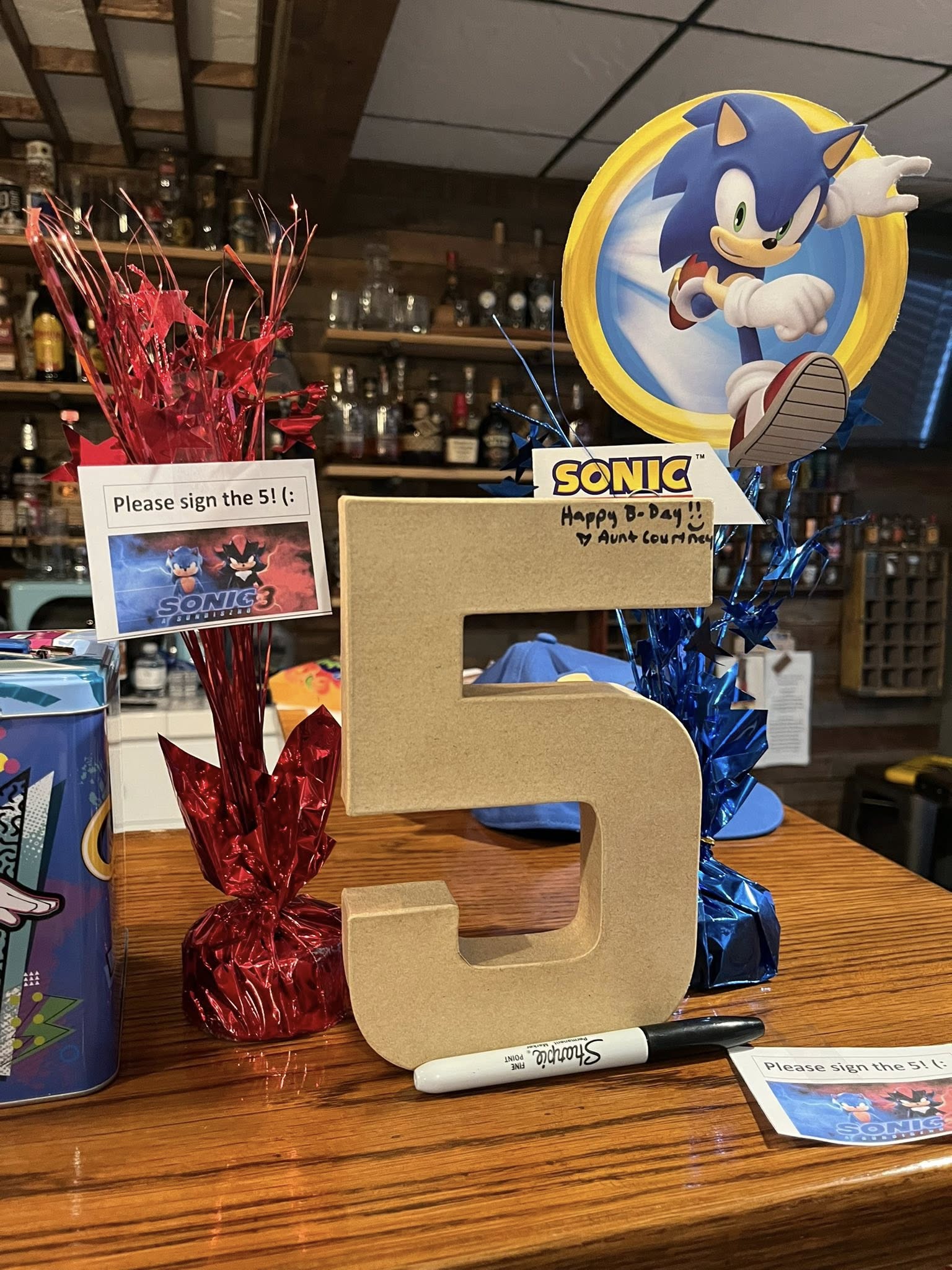 Large wooden number five with a sign reading Please sign the 5 and a Sonic the Hedgehog decoration.