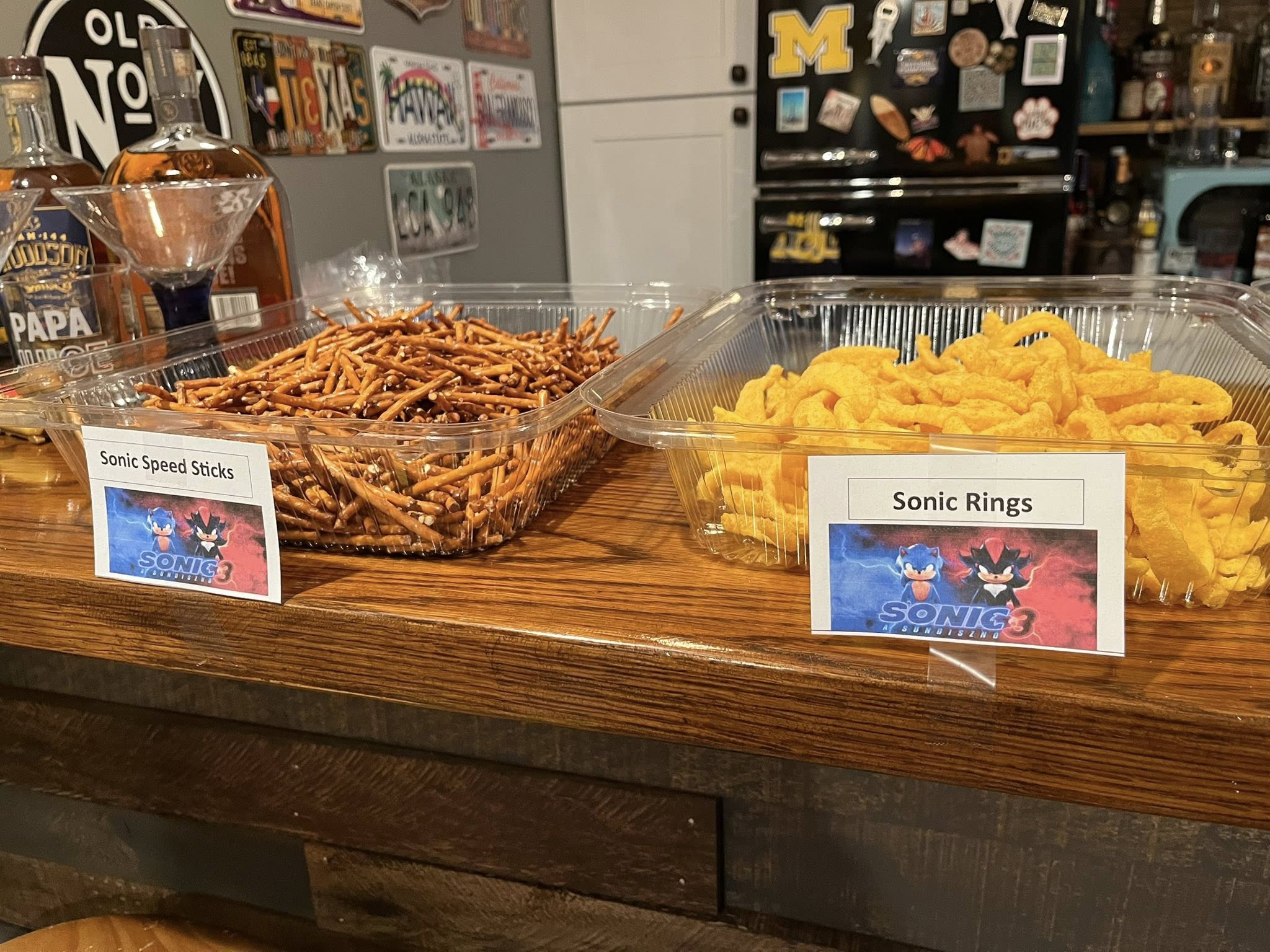 Table with clear trays of pretzel sticks labeled Sonic Speed Sticks and cheese curls labeled Sonic Rings.