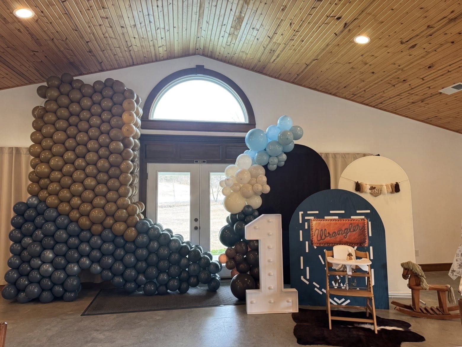 Western-themed first birthday party decor featuring a large DIY cowboy boot balloon sculpture and light-up number one.