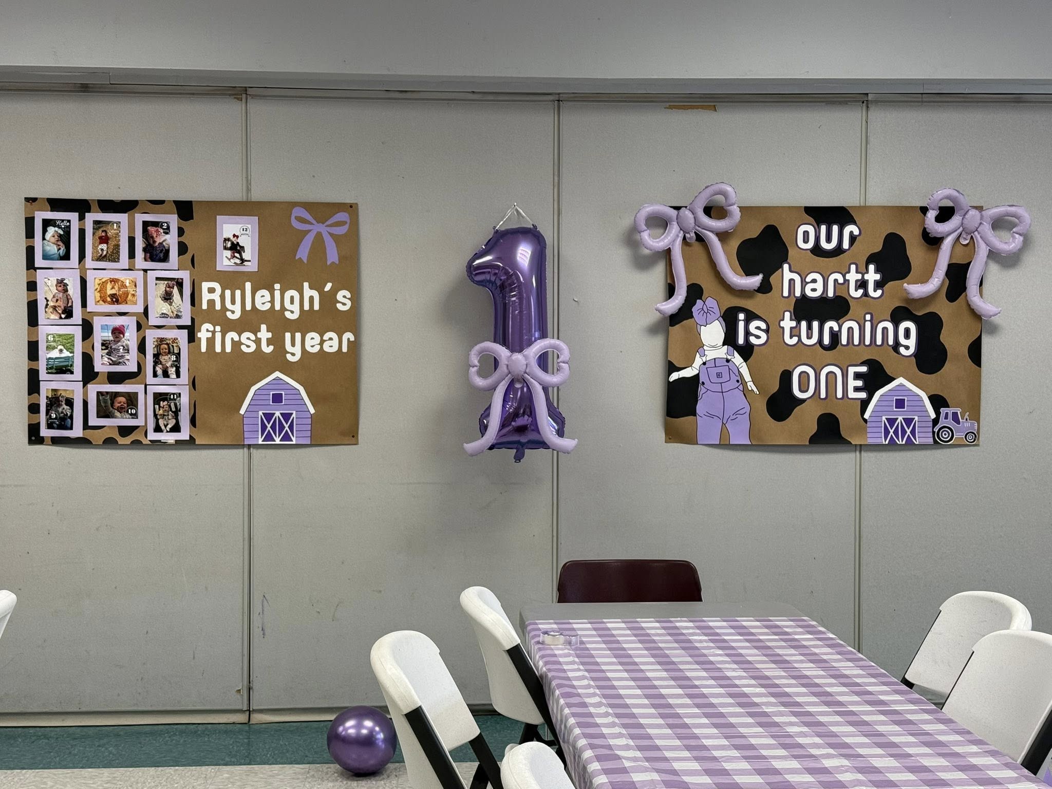 First birthday party decorations with purple cow print banners and a number one balloon.