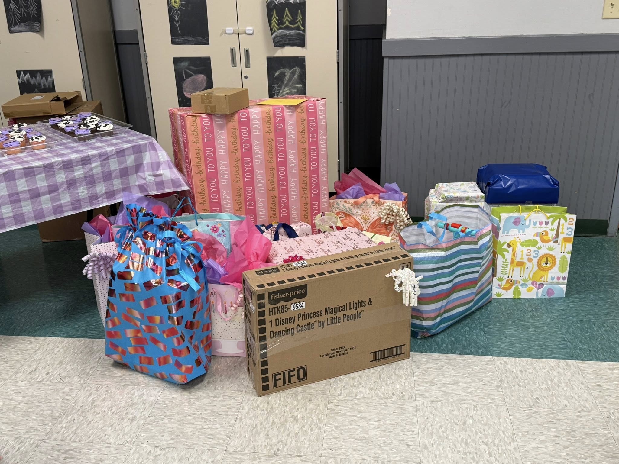 A collection of wrapped birthday presents, gift bags, and a Fisher-Price Disney Princess toy box.