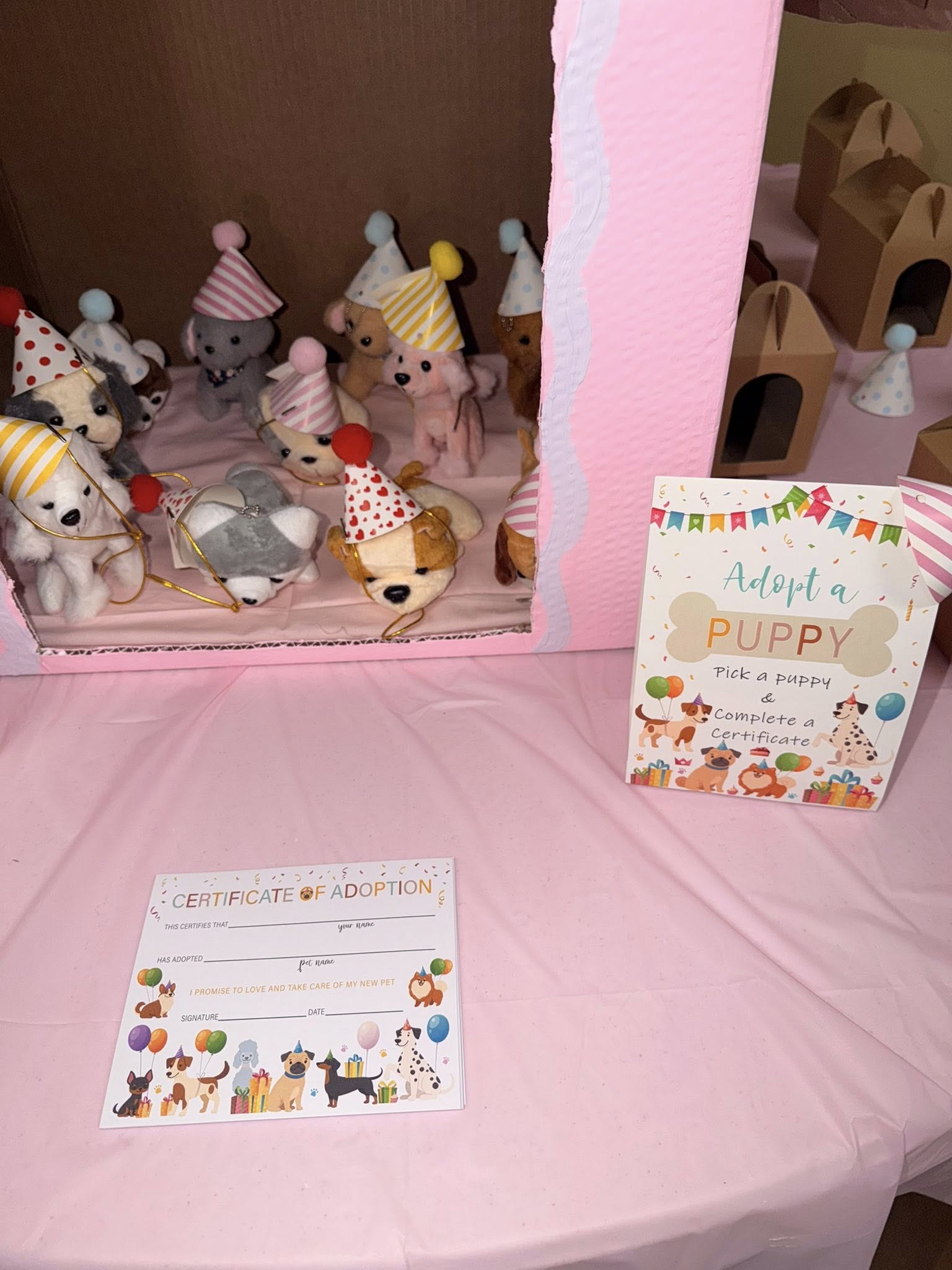 Tabletop display featuring plush puppies in party hats for an adoption party activity with certificates.