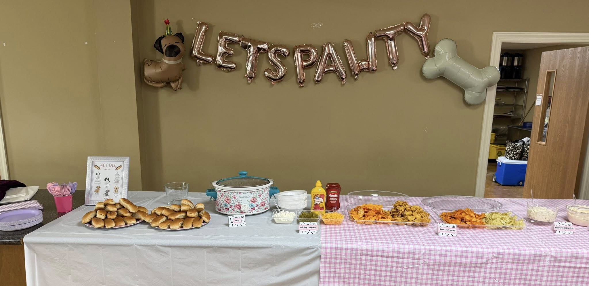 A food table set up for a dog birthday party with a 'LETS PAWTY' balloon banner.