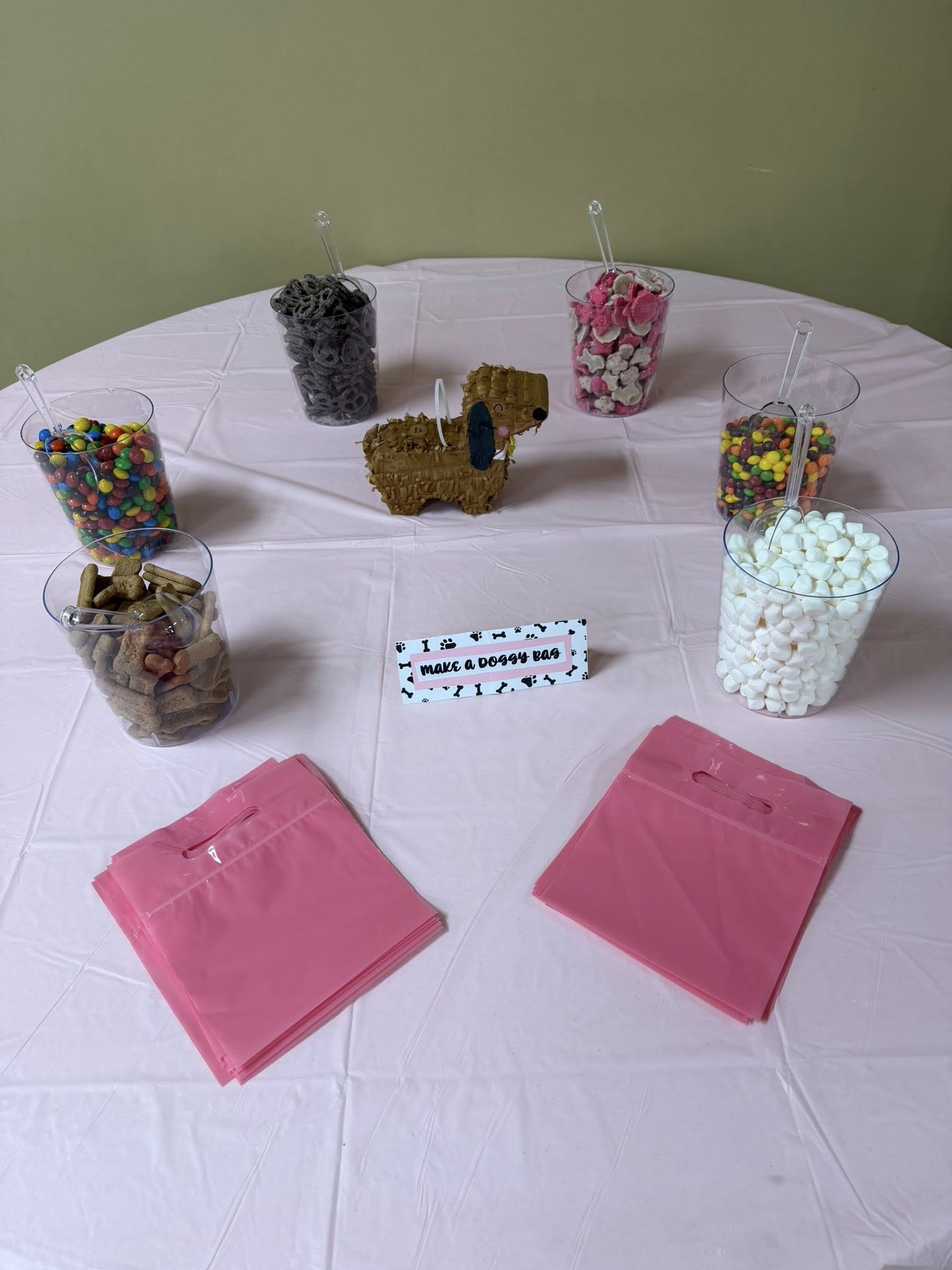 Table with a Make a Doggy Bag sign, treat jars, and pink party bags.