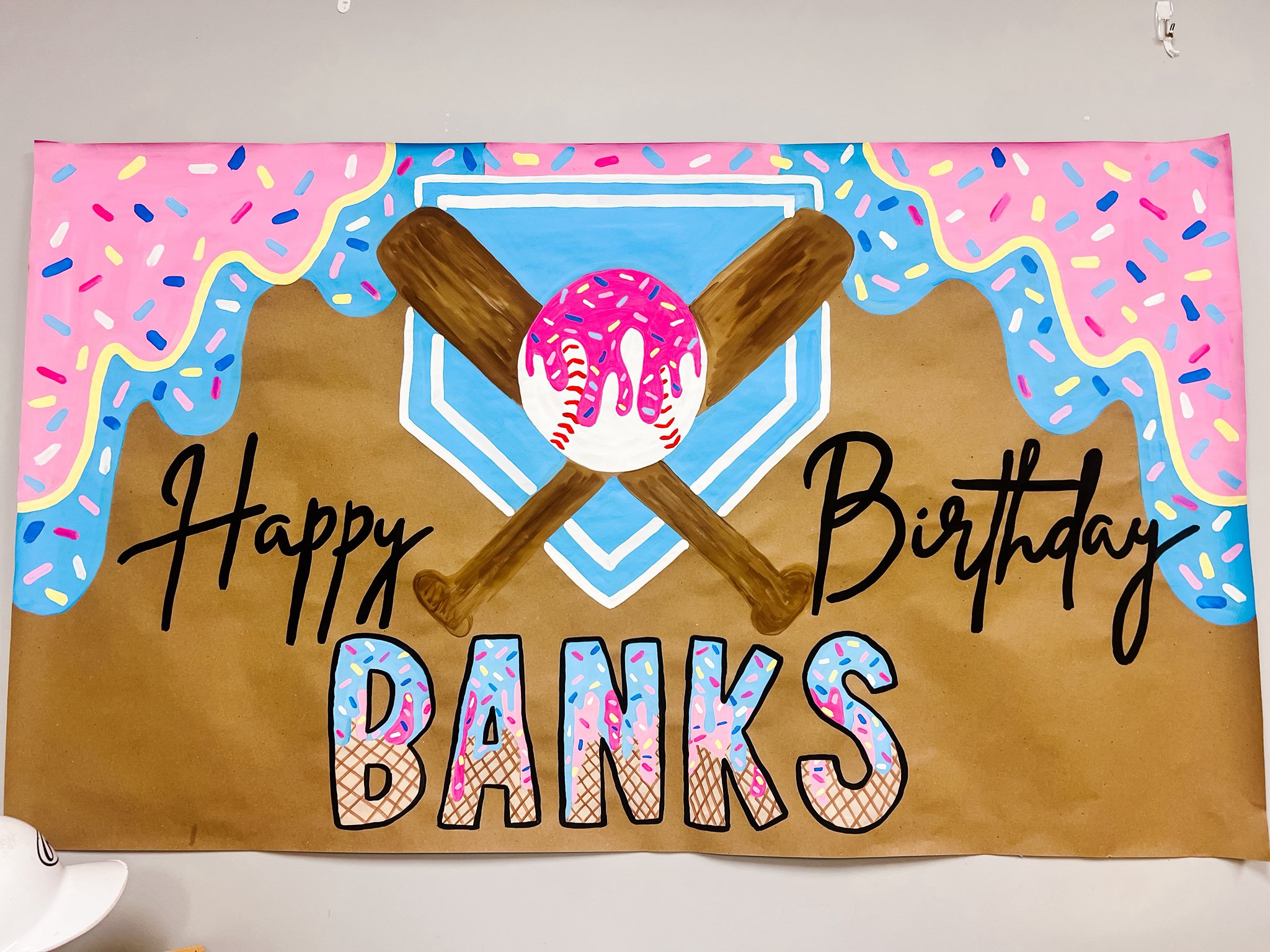 Hand-painted Happy Birthday Banks baseball banner with donut-themed decorations and crossing baseball bats.
