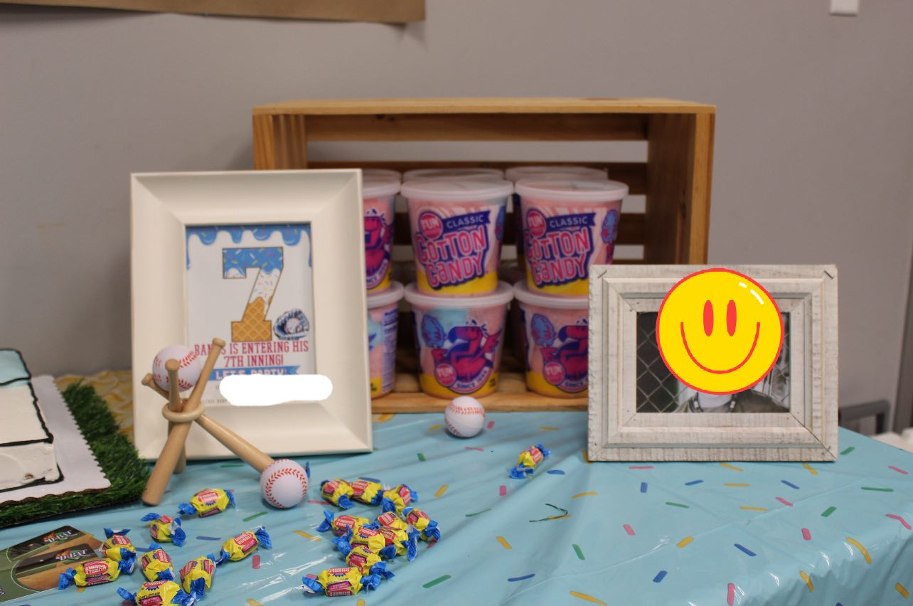 Baseball-themed birthday table decorations featuring 7th birthday signage, cotton candy, and scattered candies.