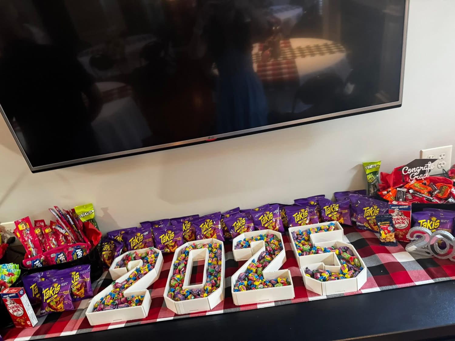 Table display featuring number-shaped boxes filled with colorful candies and surrounded by Takis snack bags.