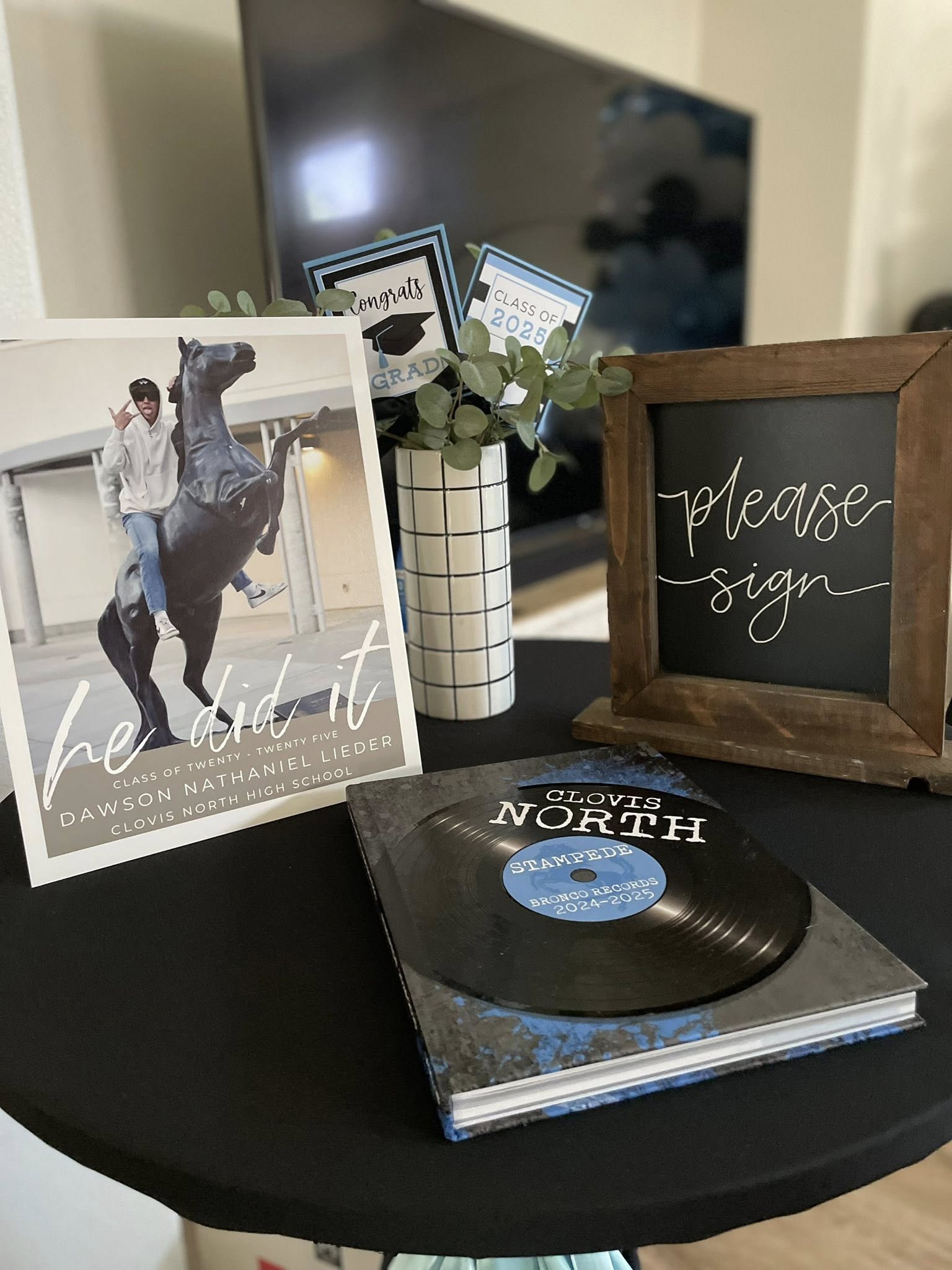 Custom high school graduation table decor featuring a photo sign, please sign blackboard, and Clovis North yearbook.