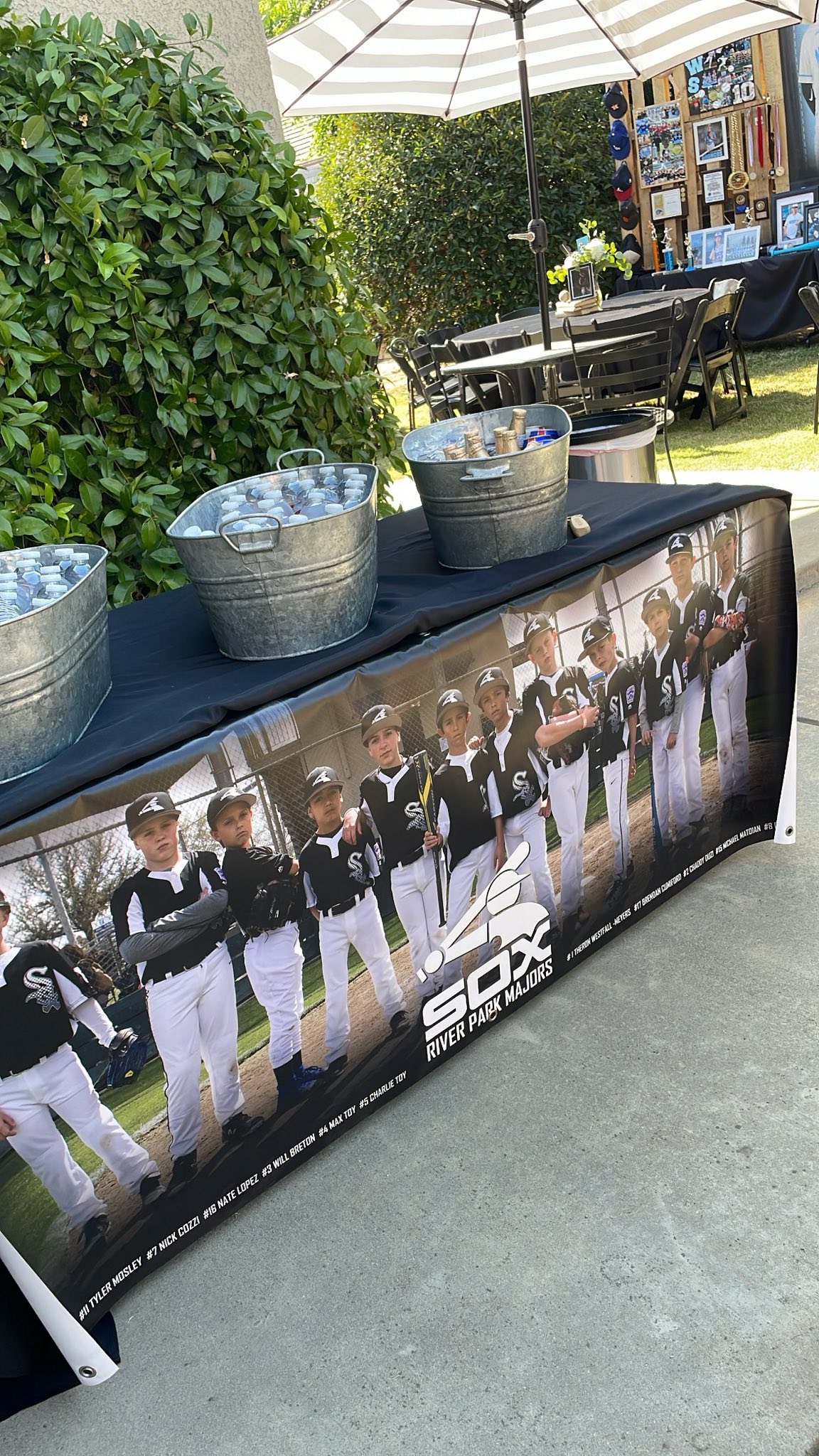 Custom River Park Majors baseball team banner displayed on a table with drink buckets.