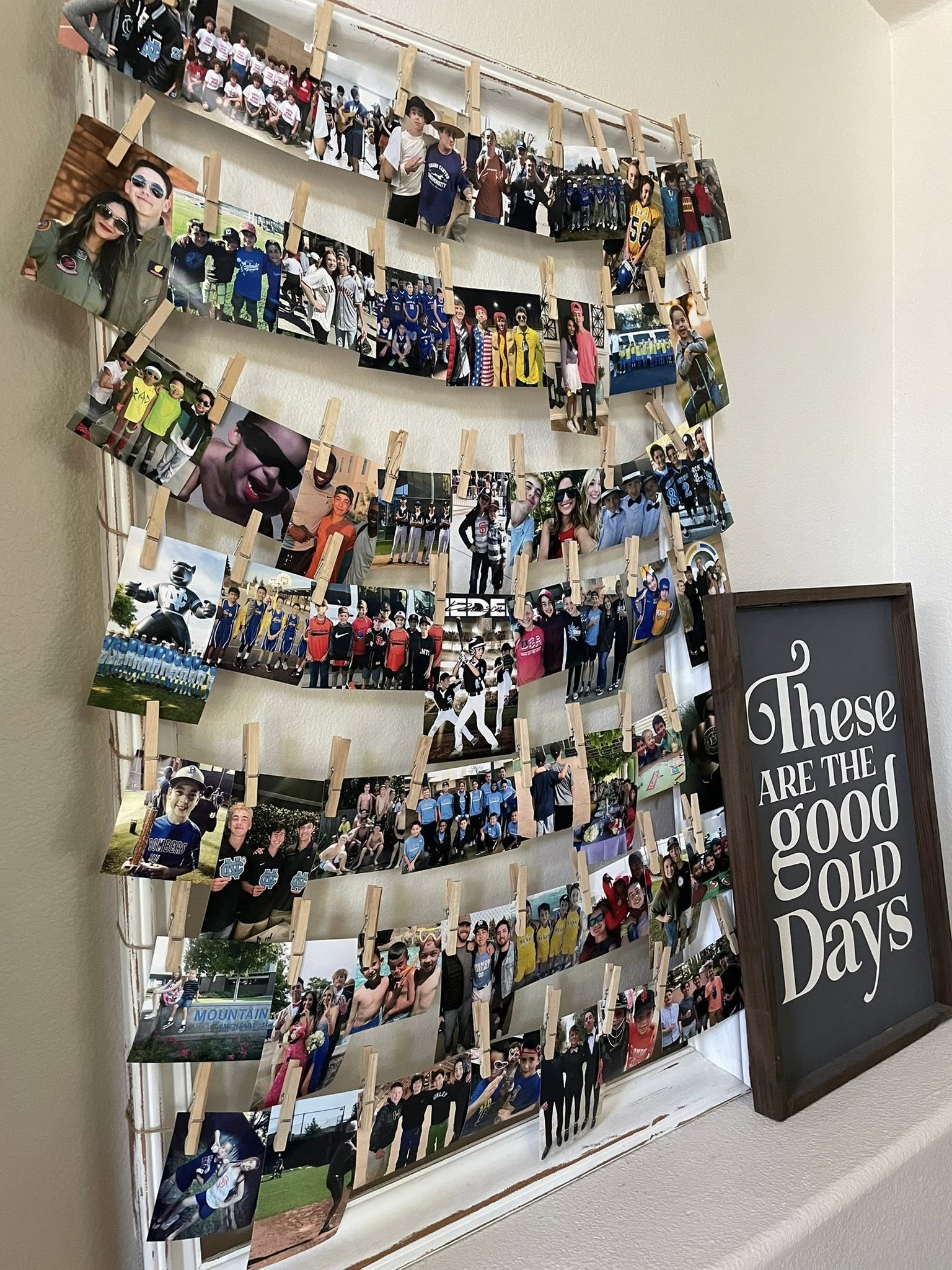 Rustic window frame display hanging multiple photographs with wooden clips next to a These Are The Good Old Days sign