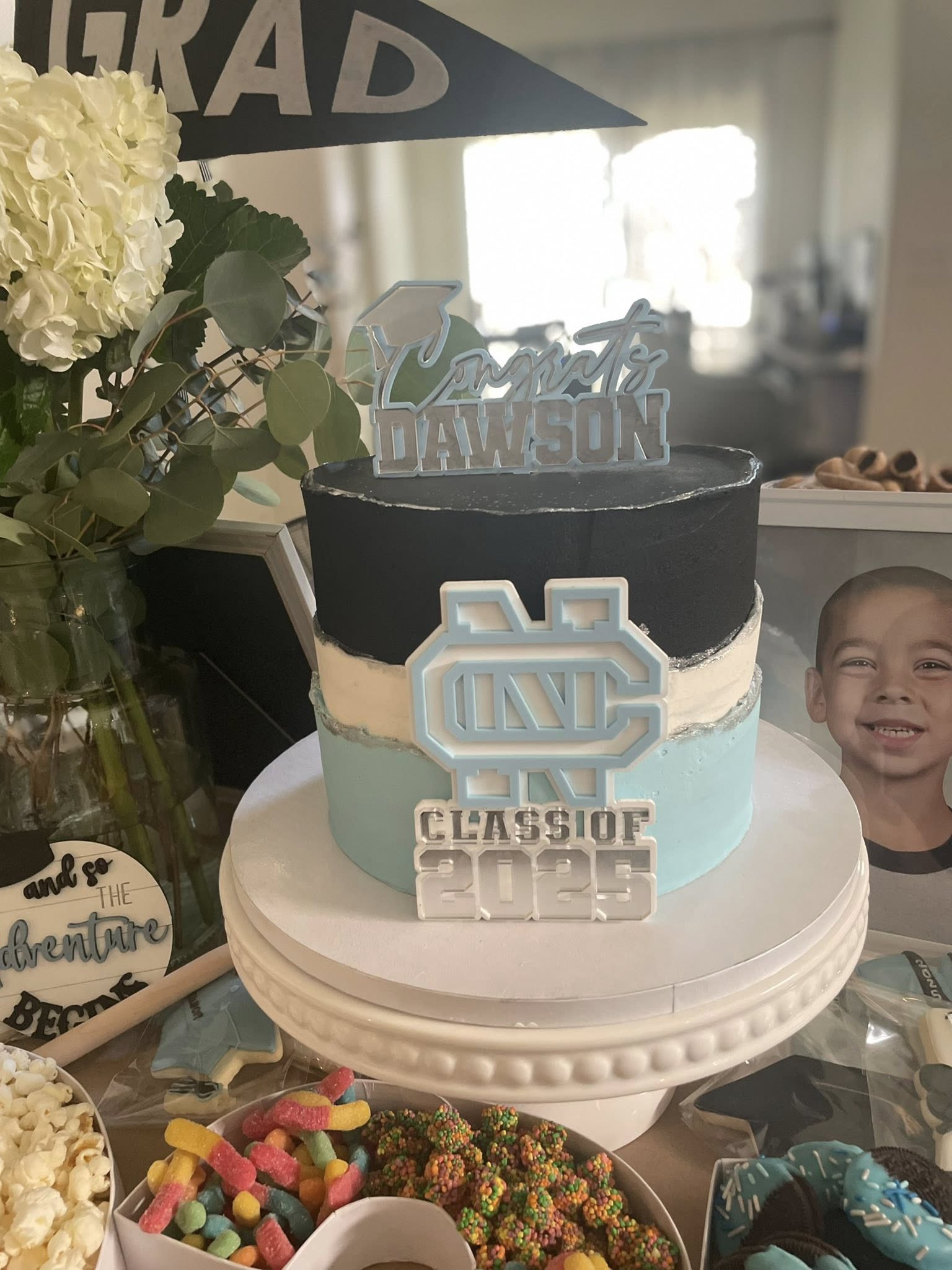 Graduation cake featuring black, white, and light blue layers with a custom Class of 2025 UNC topper.