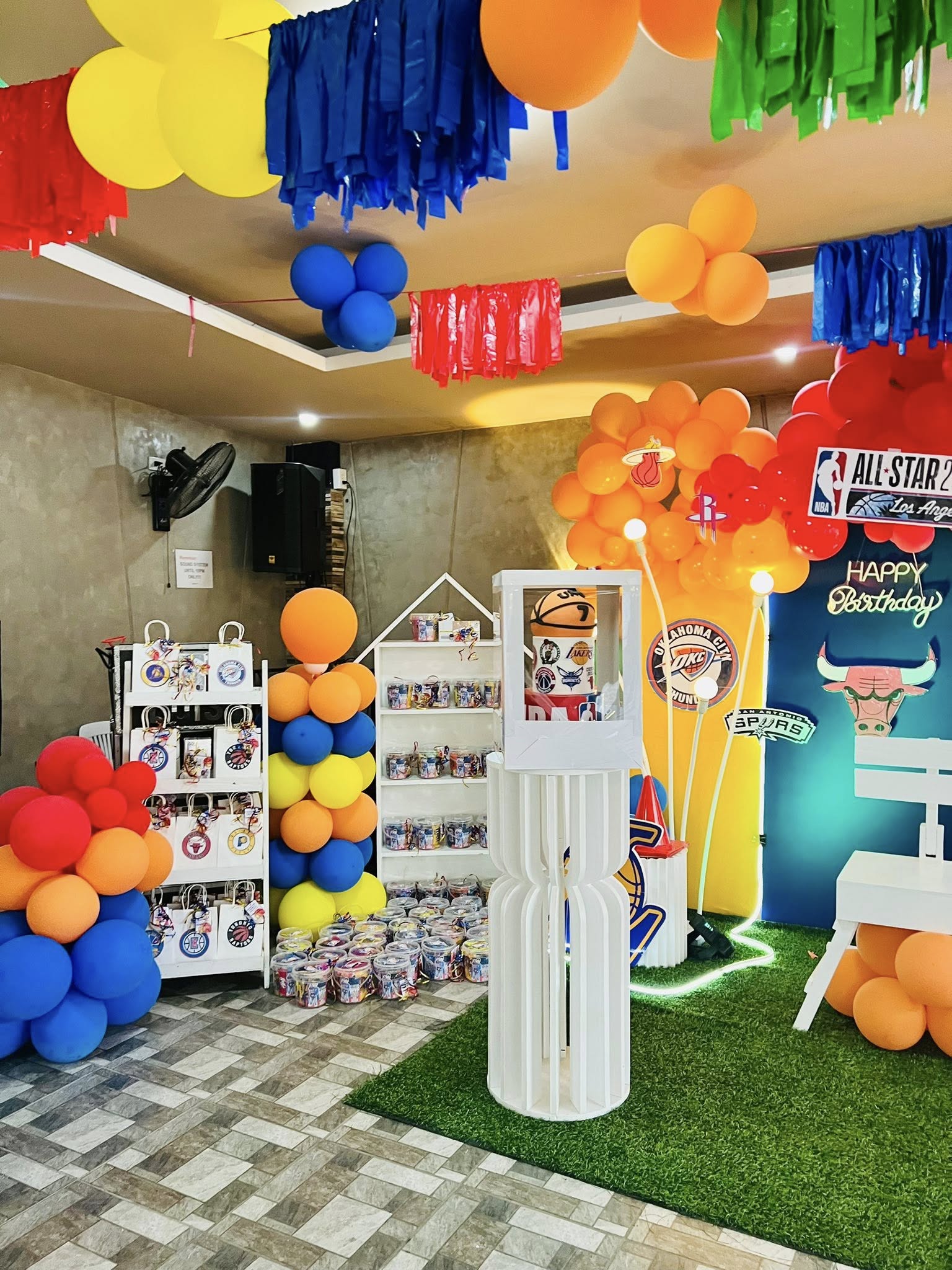 Basketball themed birthday party setup with balloon arches, sports team party favor bags, and a centerpiece.