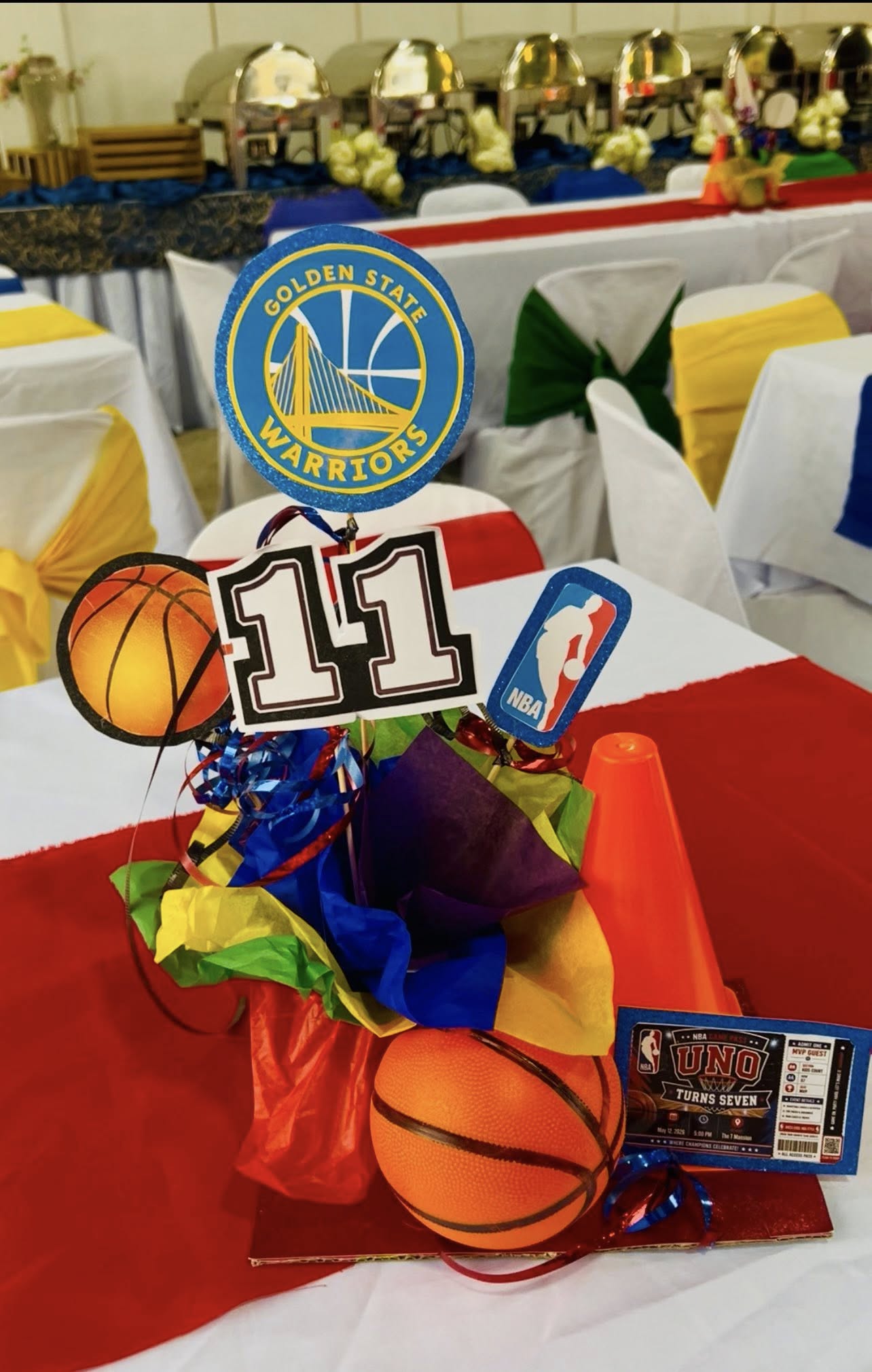 Table centerpiece themed for a Golden State Warriors 11th birthday party featuring basketballs and NBA accents.