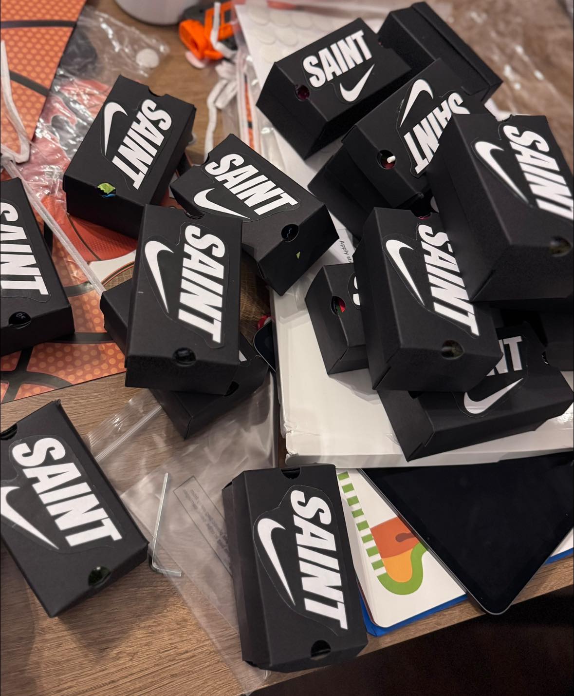 Stack of black Saint brand mini sneaker boxes with white logos stacked on a table.
