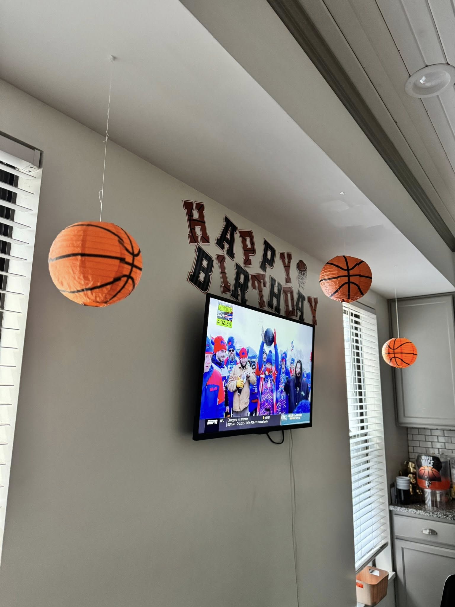 Basketball-themed paper lanterns hanging above a TV with birthday decorations on the wall