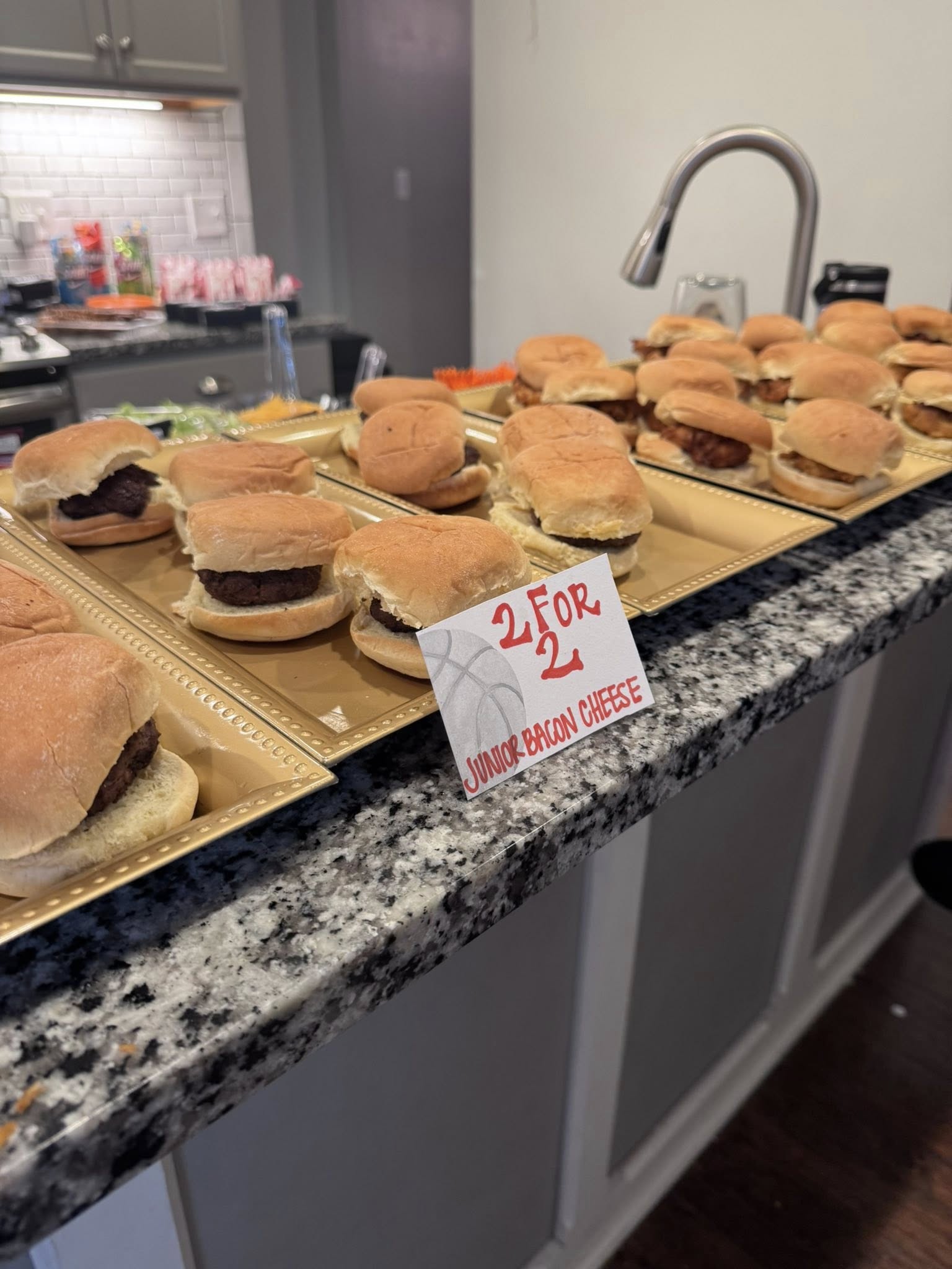 Tray of junior bacon cheeseburger sliders with a sign advertising 2 for 2 dollars