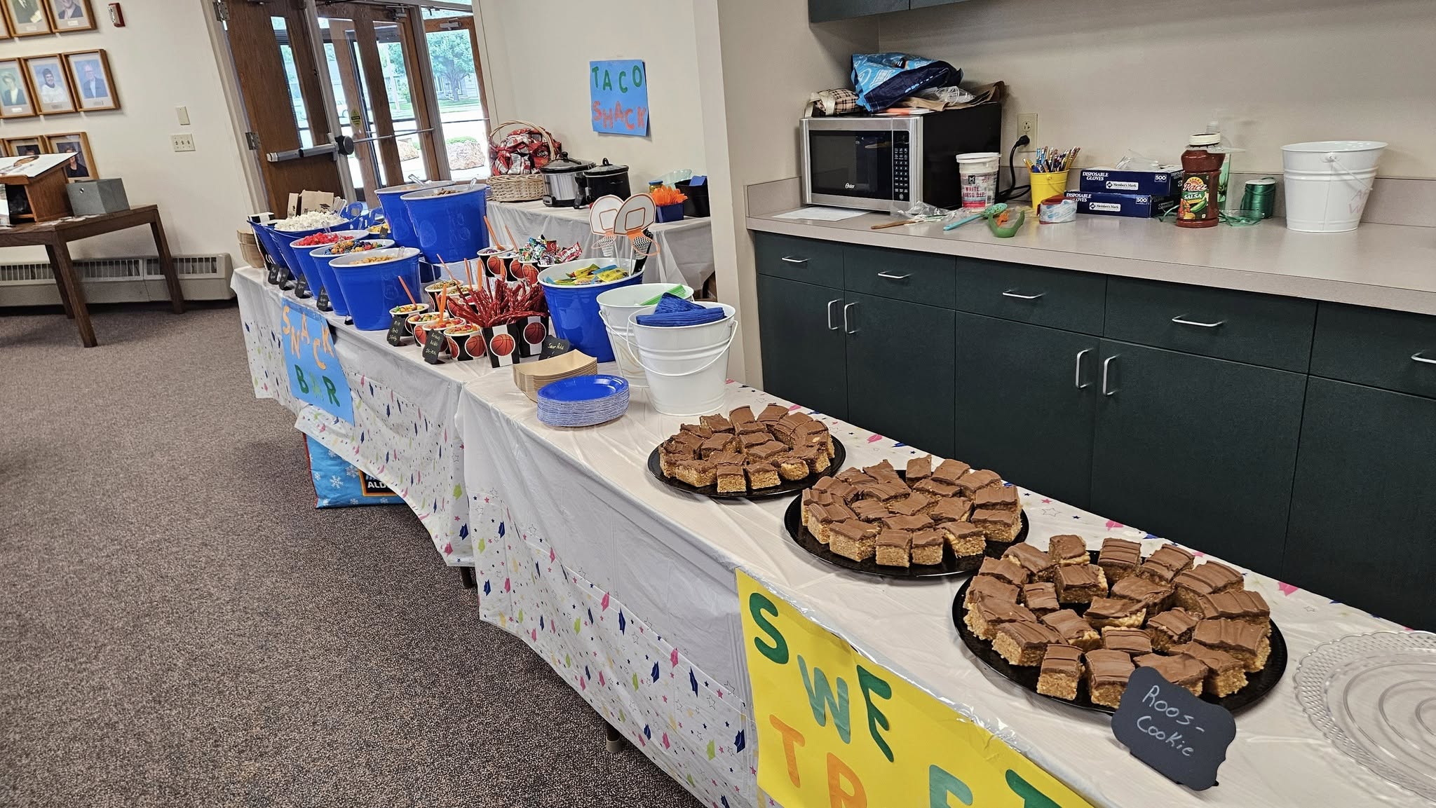 A snack bar and sweets table featuring chocolate-topped treat bars, themed snacks, and decorations.