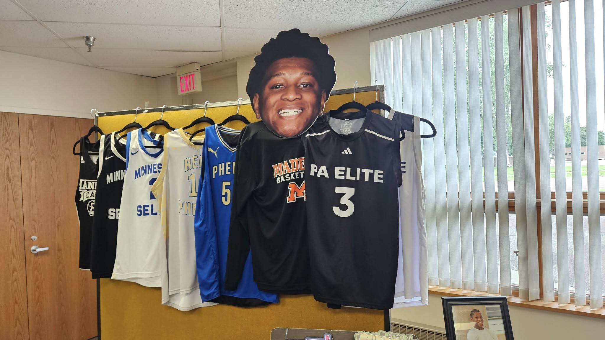 Display rack featuring various youth basketball jerseys and a large cutout head of a player