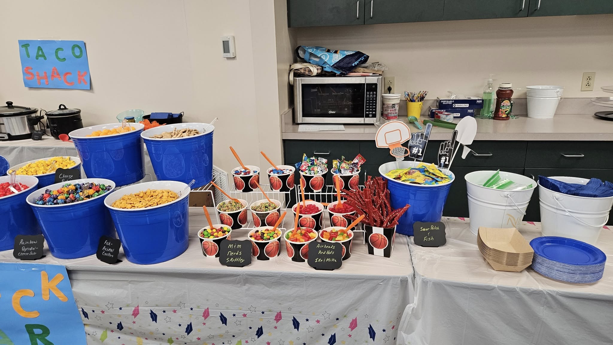 Table spread with blue and basketball-themed snack buckets filled with various candies and crackers for a party.