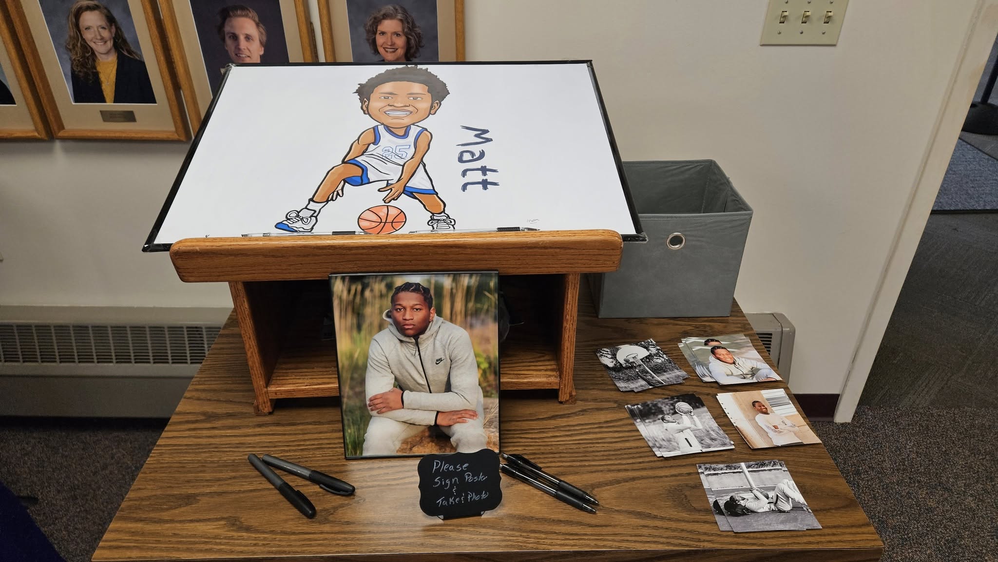 A basketball-themed graduation station featuring a caricature poster, senior photos, and a sign asking guests to leave a message.