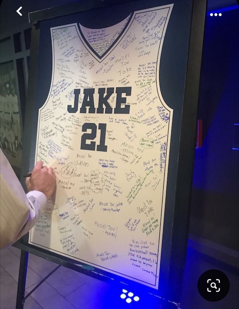 Custom basketball jersey signing board personalized for Jake with number 21, covered in handwritten messages.