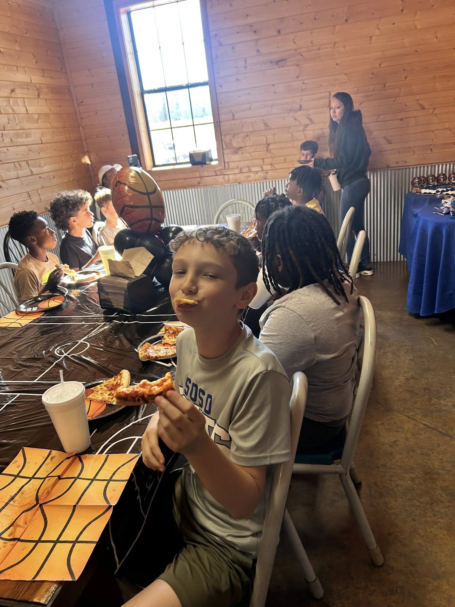 Boy enjoying pizza at a basketball themed birthday party