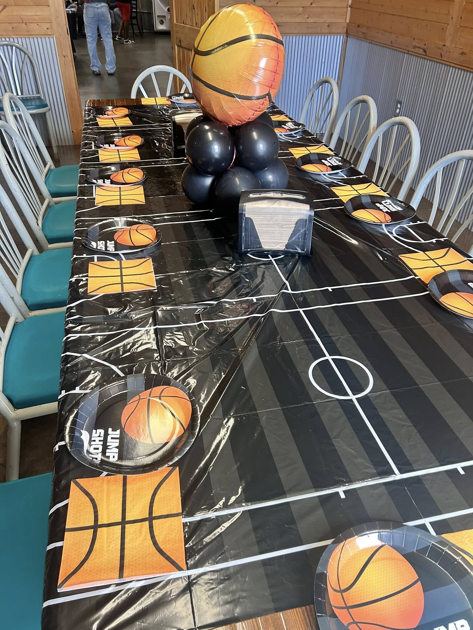 Basketball themed party table setting with court pattern tablecloth, hoop plates, and balloon centerpiece.