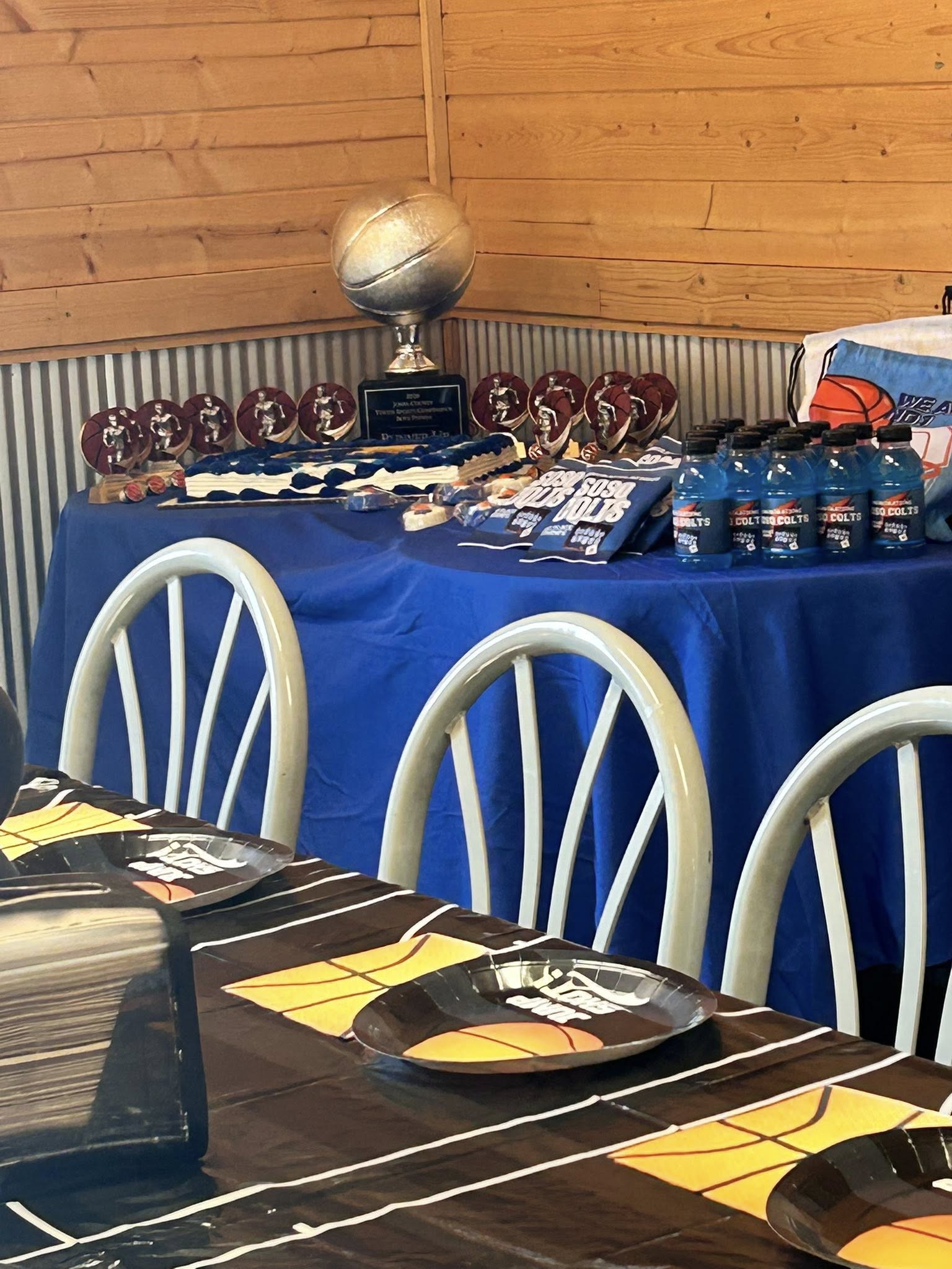 Table decorated for a basketball themed party with a trophy, team snacks, and drinks.