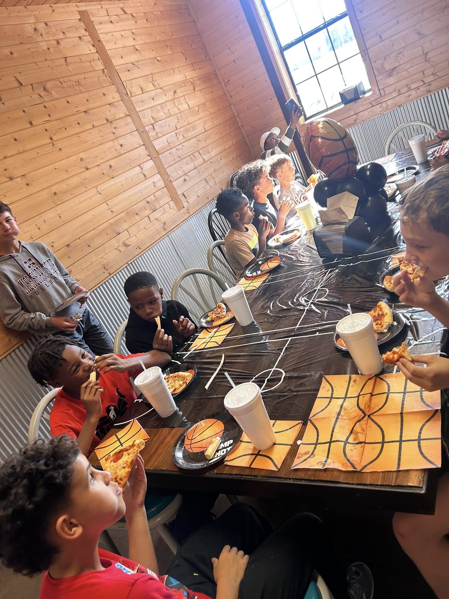 Group of children eating pizza at a basketball-themed birthday party celebration