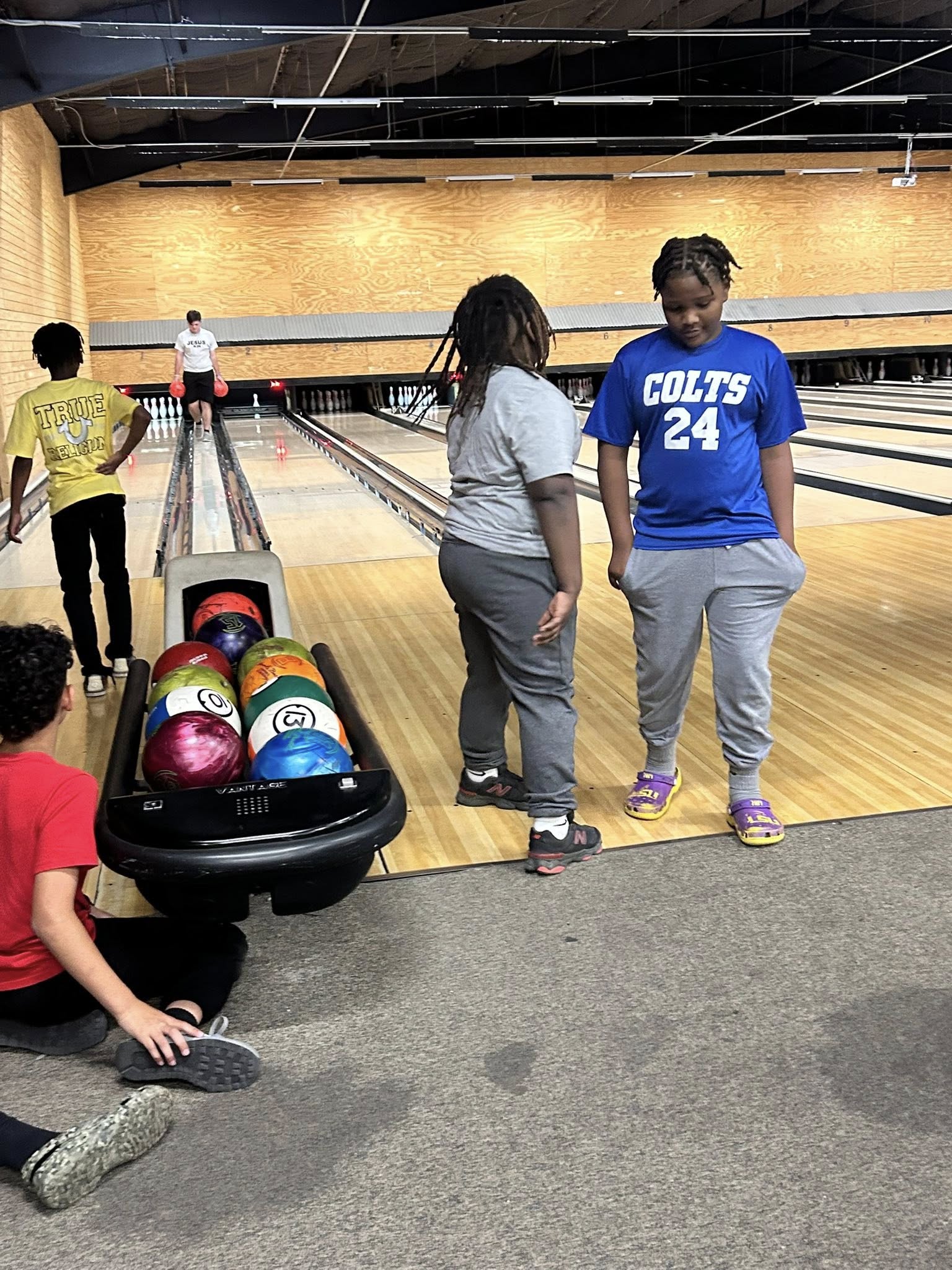 Group of kids bowling at an indoor bowling alley with bowling balls in the ball return rack