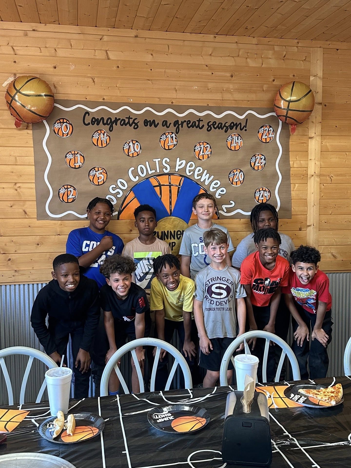 Group of young youth basketball players smiling at a team end-of-season party.