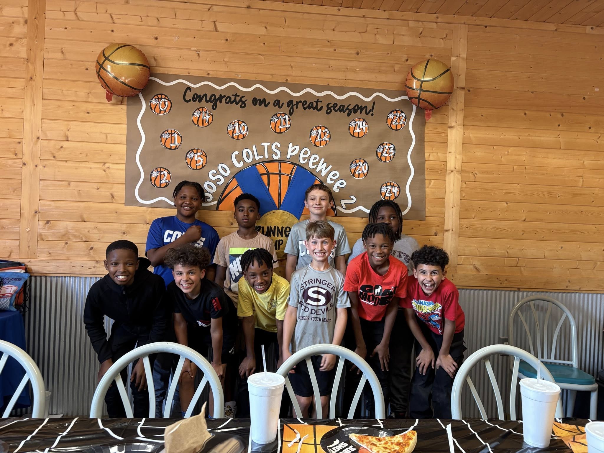 Group of young Ooso Colts Peewee basketball players posing at a team season celebration.